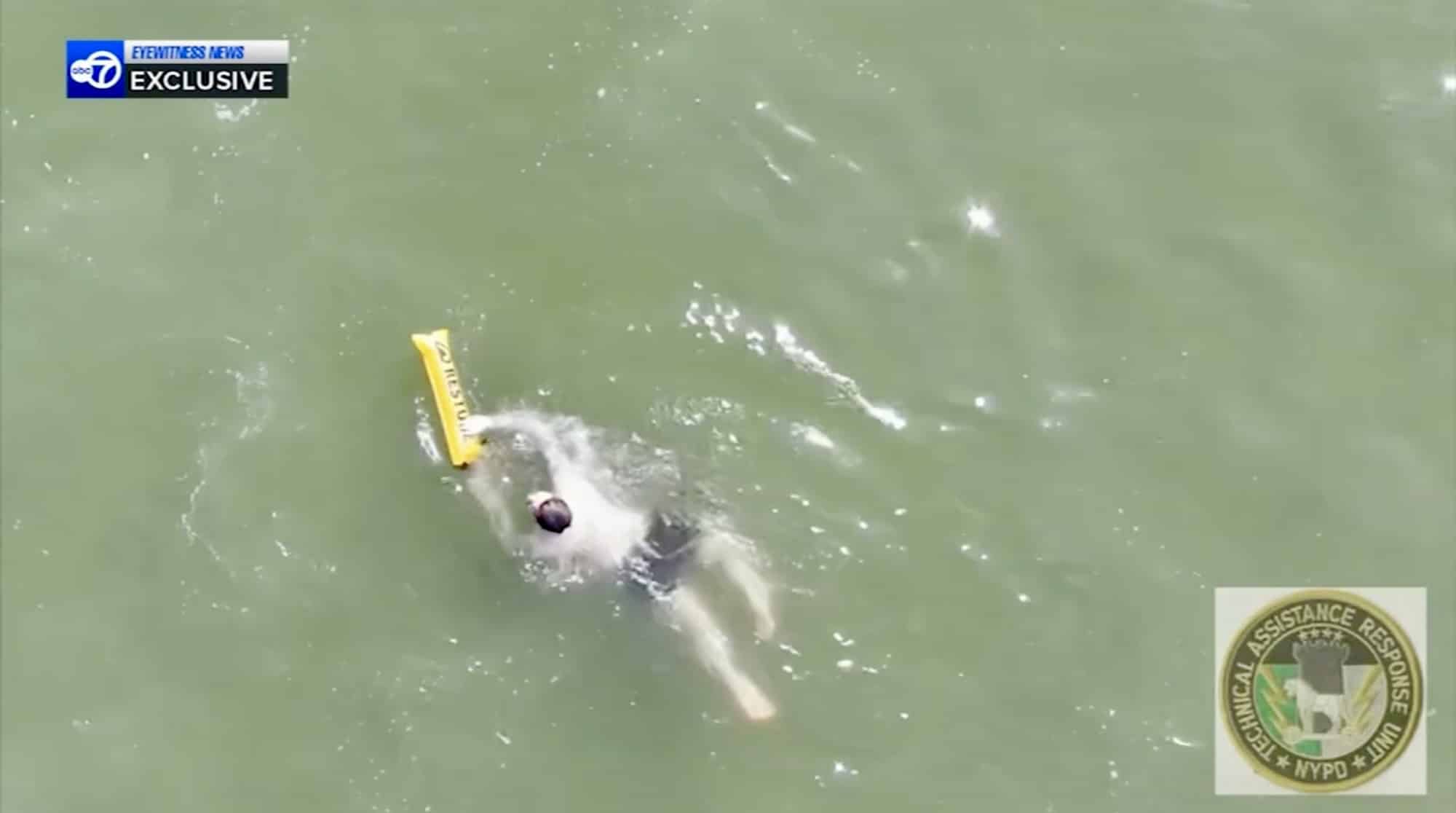 Aerial view of a swimmer in the surf reaching the dropped yellow float.