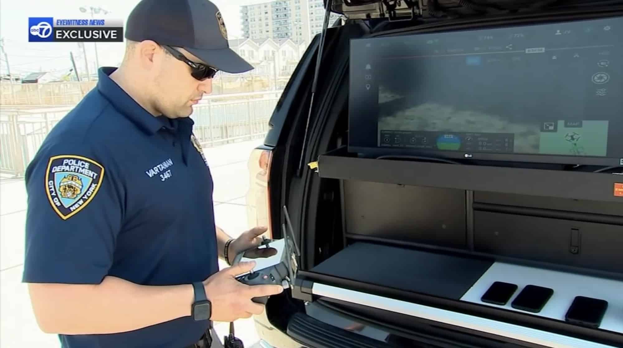 NYPD officer working a controller at the open tailgate of an SUV command vehicle.