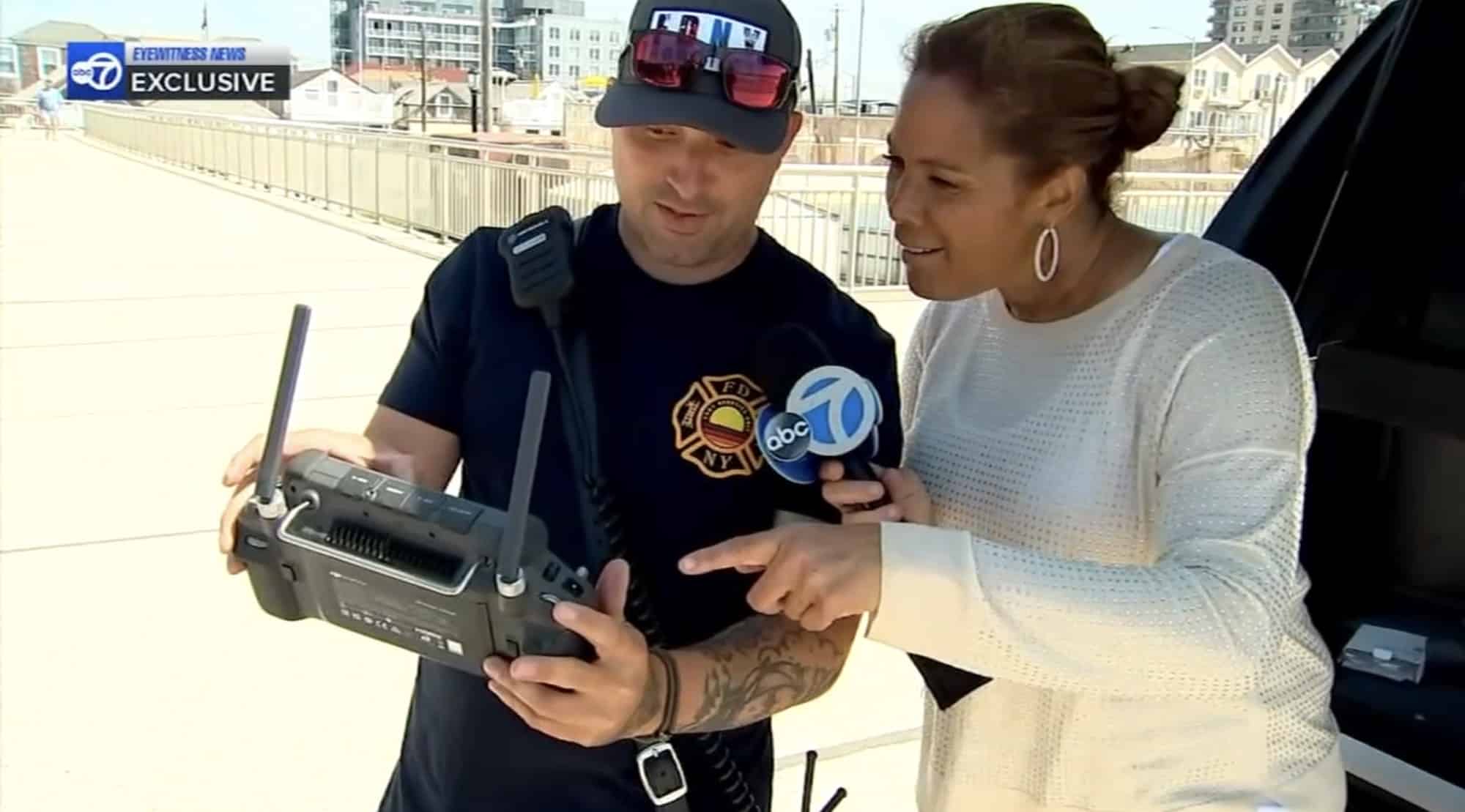 Firefighter with a DJI controller answering questions from an ABC7 reporter holding a microphone.