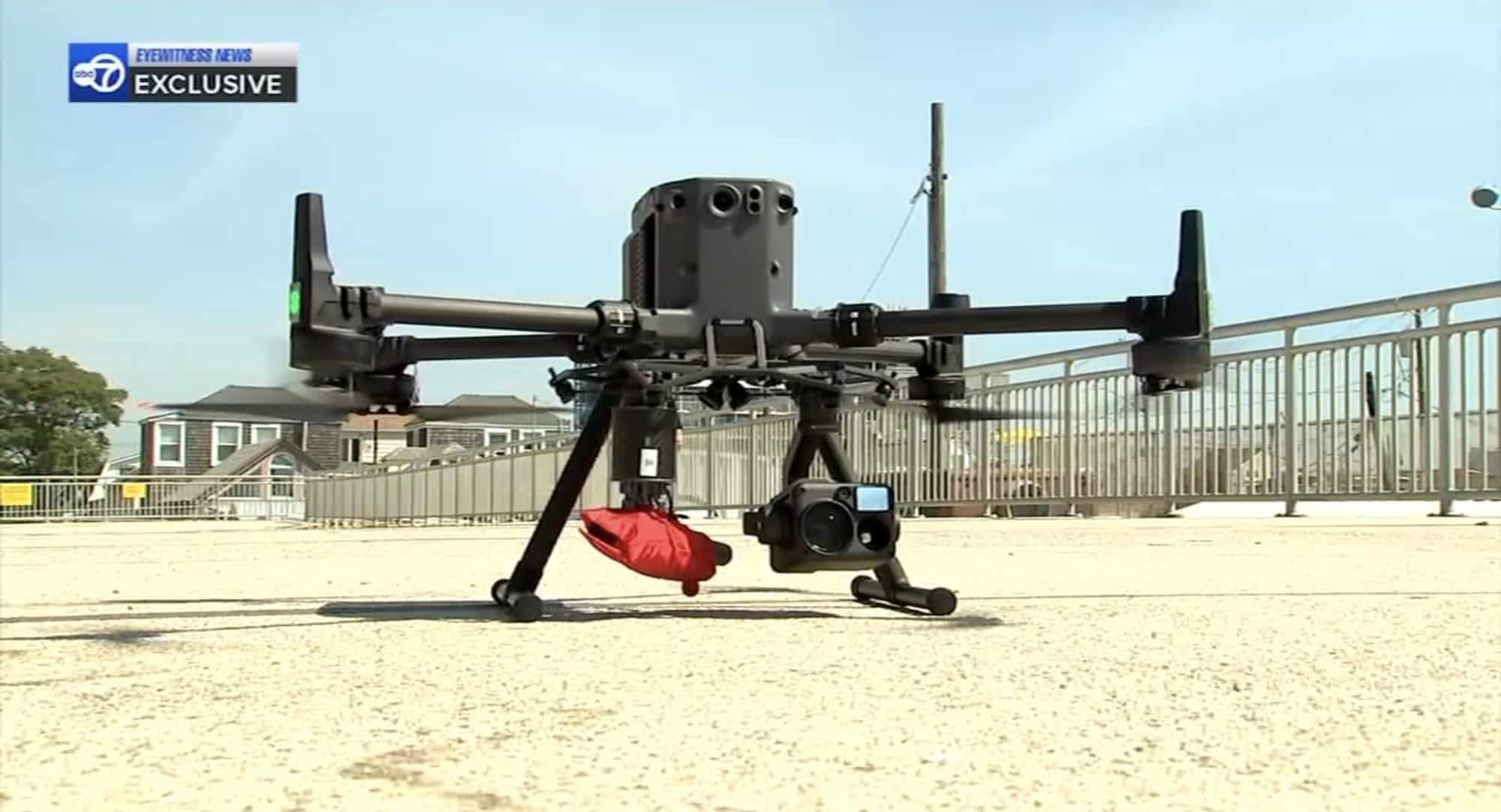 DJI Matrice parked on the sand with a red rescue float slung underneath.