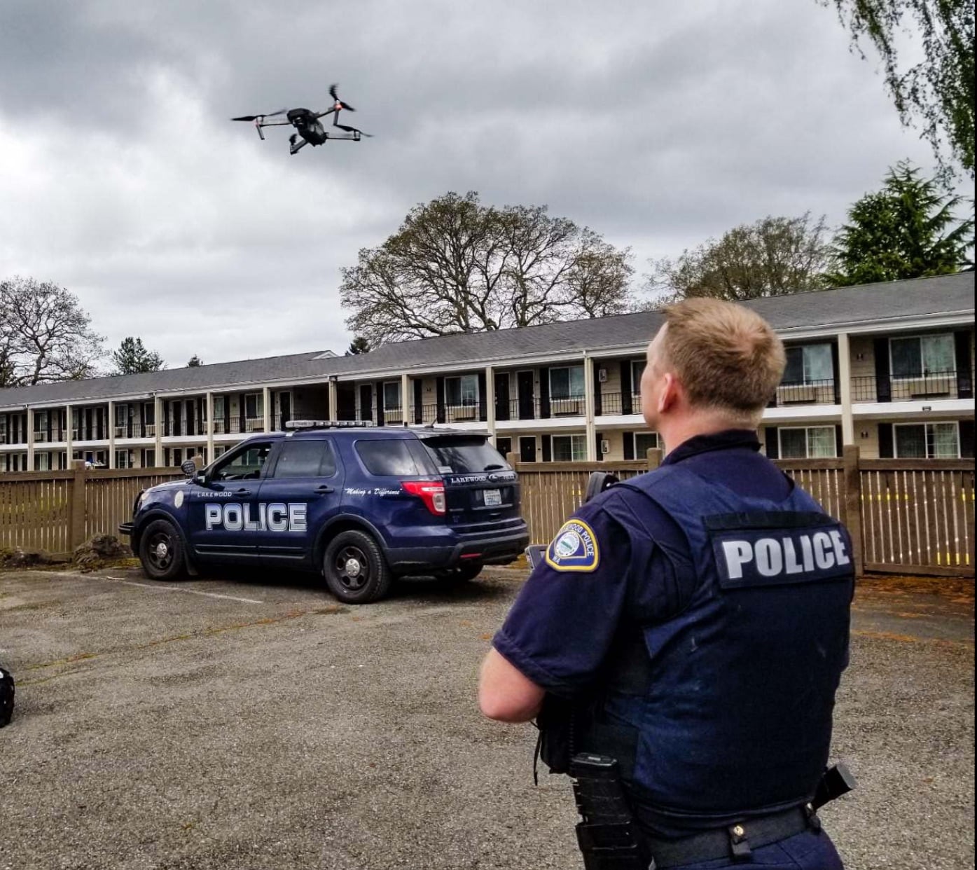 Lakewood police officer watching a drone above a patrol SUV outside a motel.