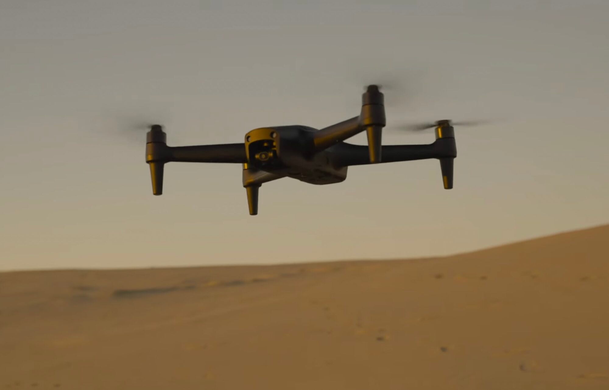 Aeroo Pro hovering above desert dunes in warm low-angle light.