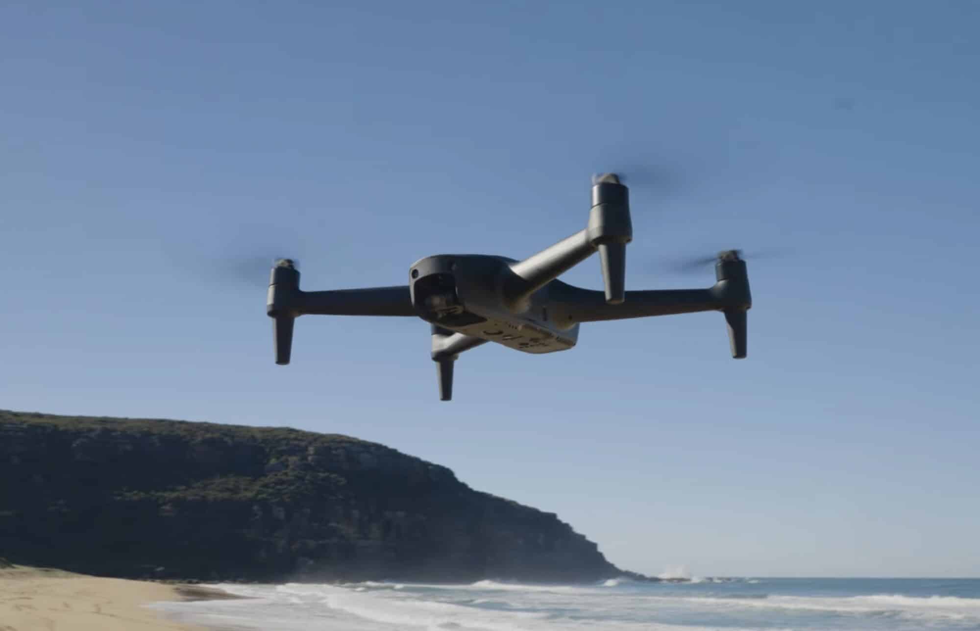 Aeroo Pro flying over a beach with surf breaking below coastal cliffs.