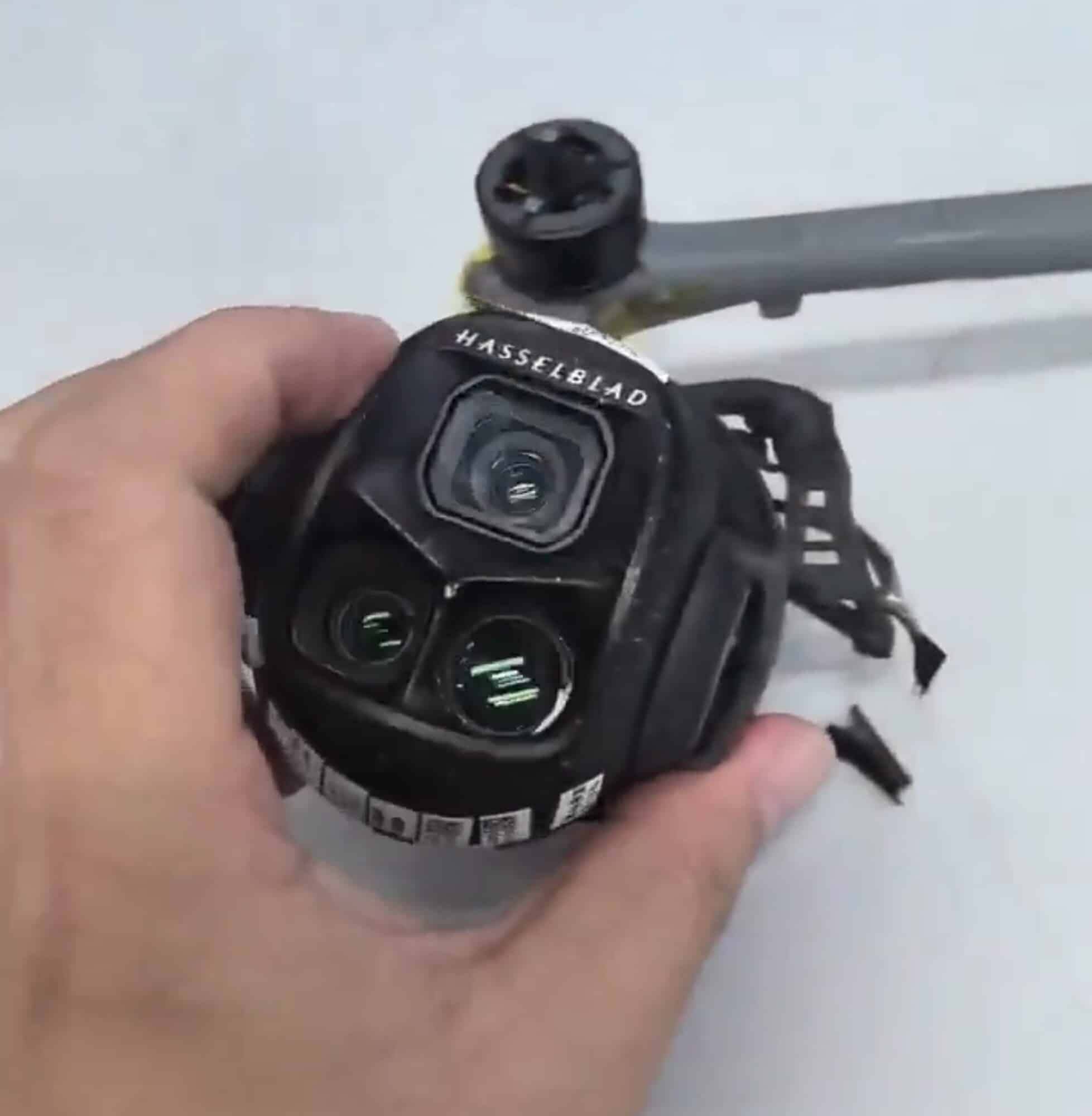 Hand holding the prototype gimbal with Hasselblad branding and a triple lens cluster.