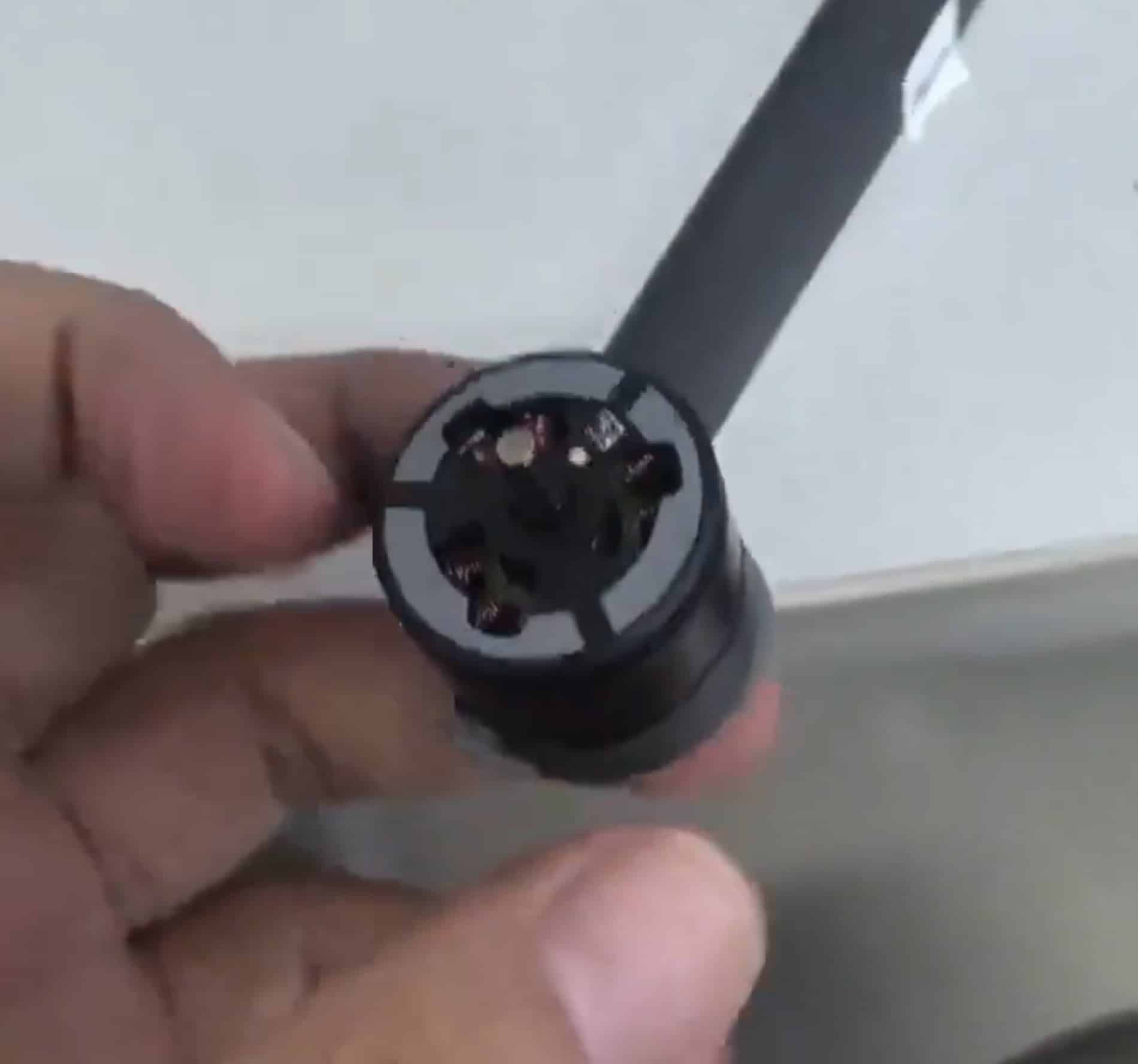 Fingers holding a bare brushless motor pulled from one of the arms.