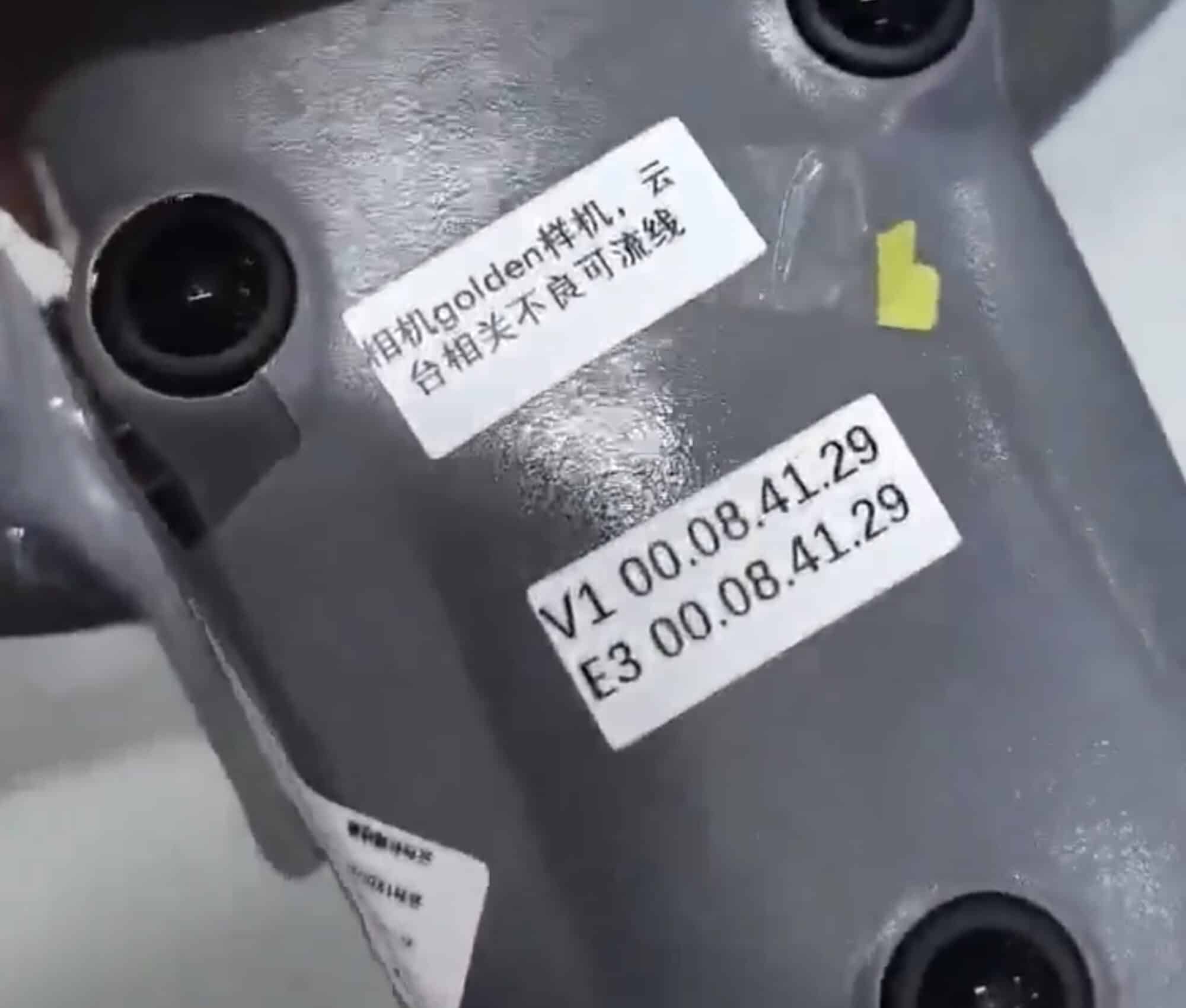 Close-up of a prototype label reading V1 00.08.41.29 beside Chinese handwriting.