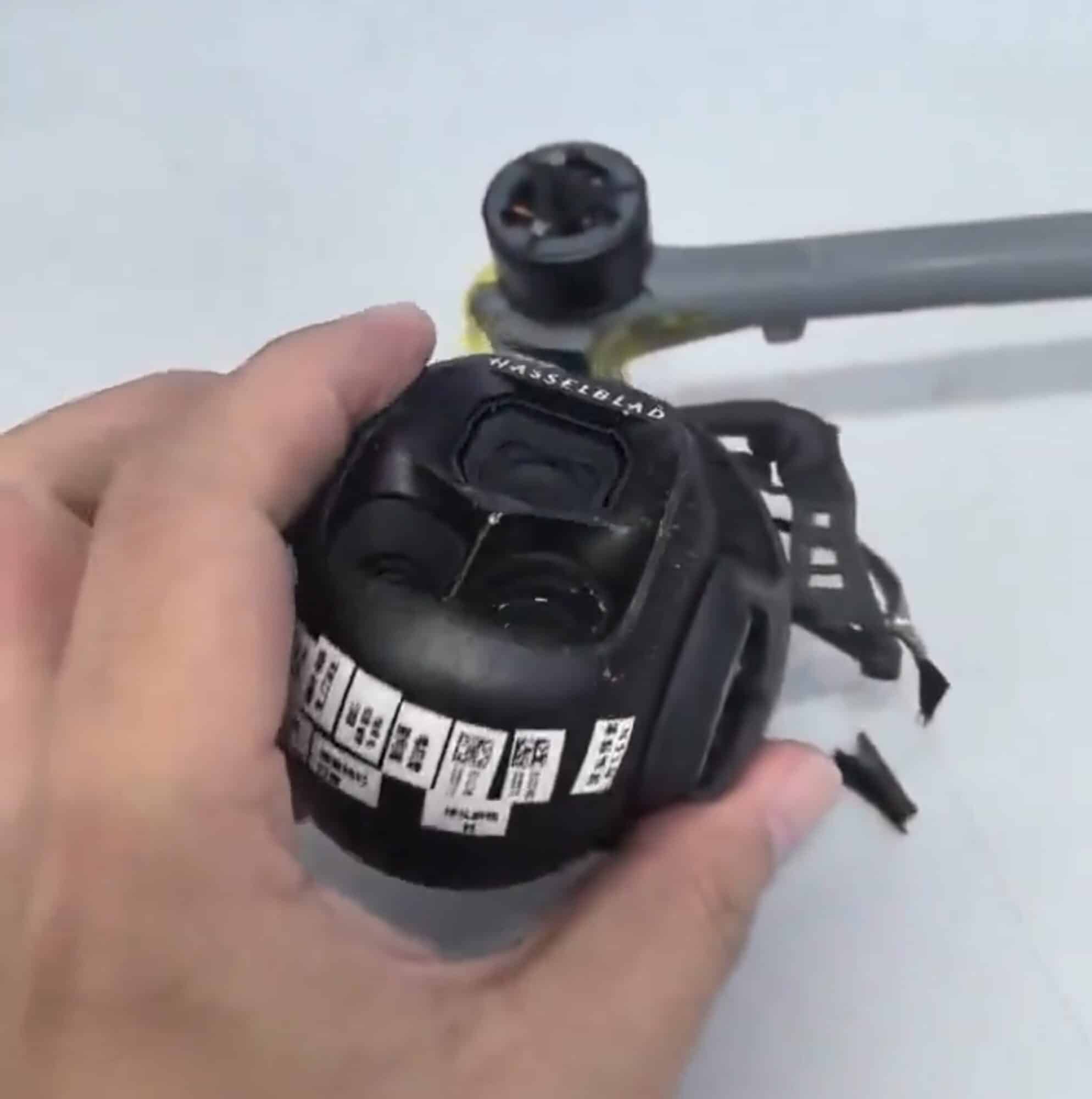 Prototype camera module tilted upward, factory labels wrapped around the gimbal housing.