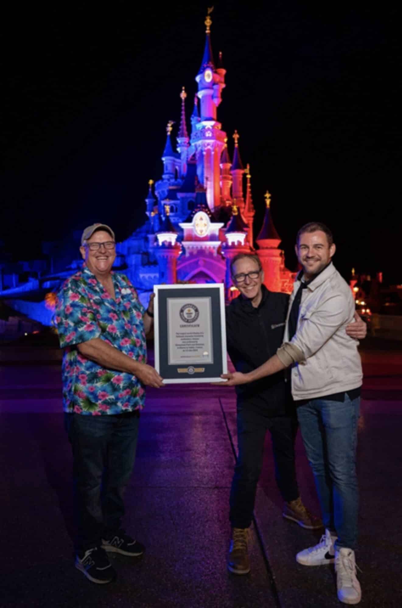 Three Disneyland Paris representatives hold a Guinness World Records certificate before the castle.