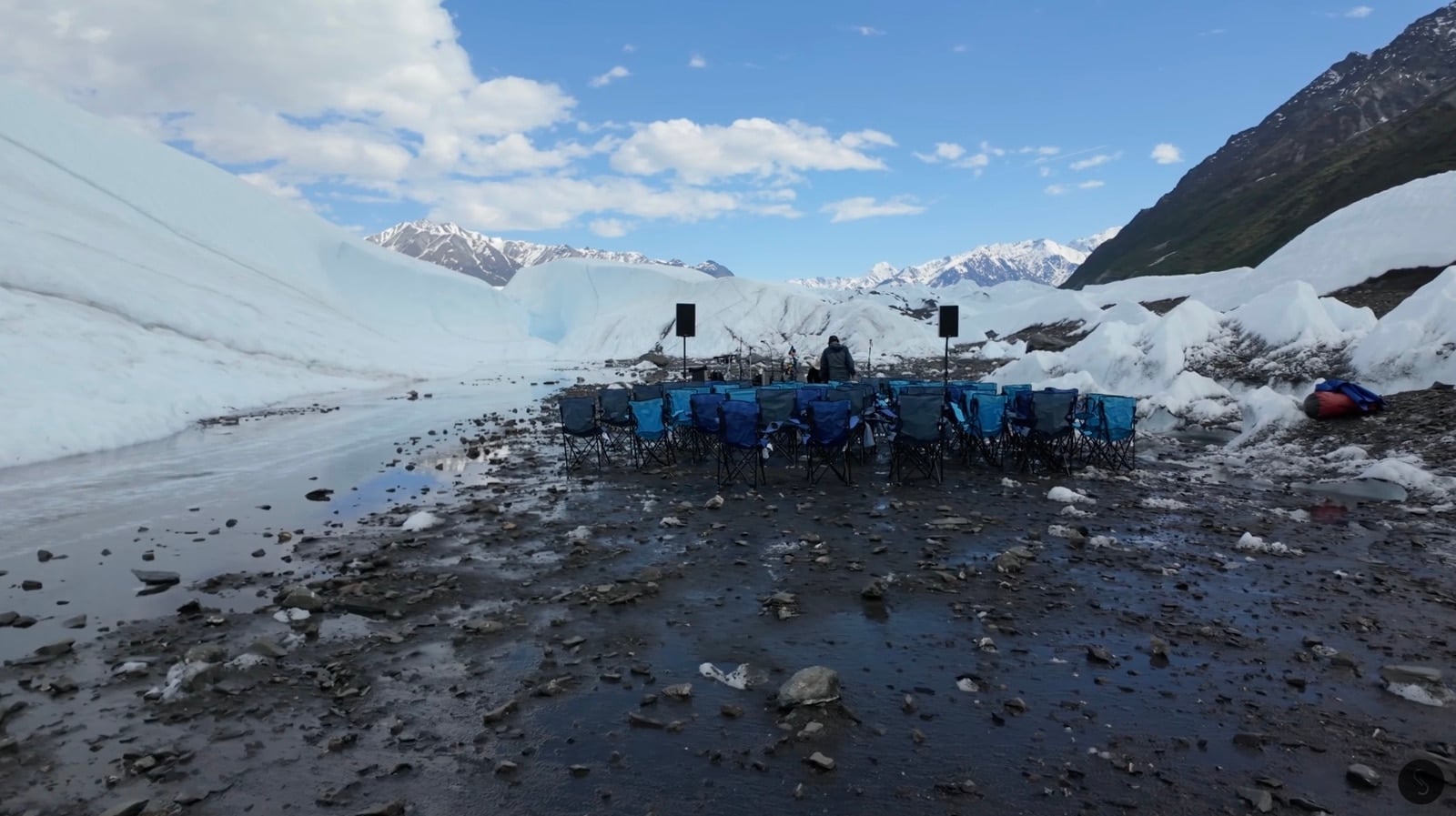 Rows of blue camp chairs and PA speakers set out on the glacier.