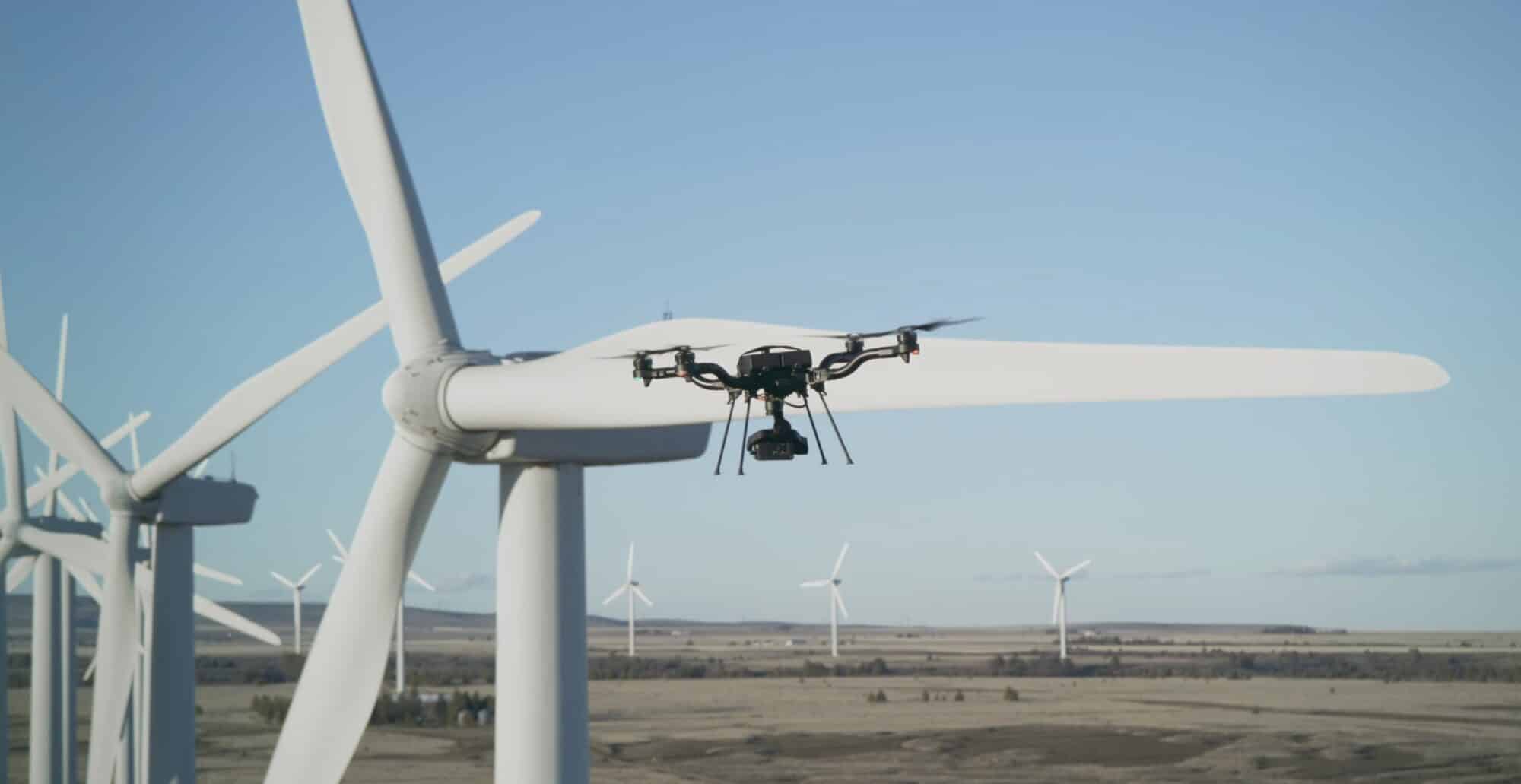Astro Prime hovering beside a wind turbine blade at a prairie wind farm.