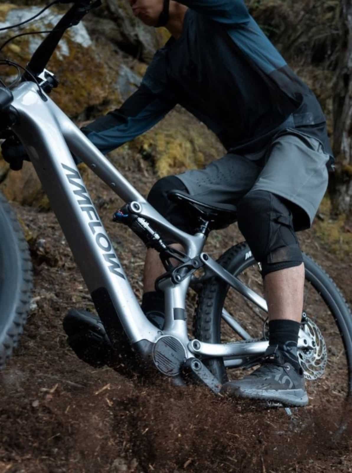 A rider climbs a dirt slope on an Amflow e-bike, drive unit visible.