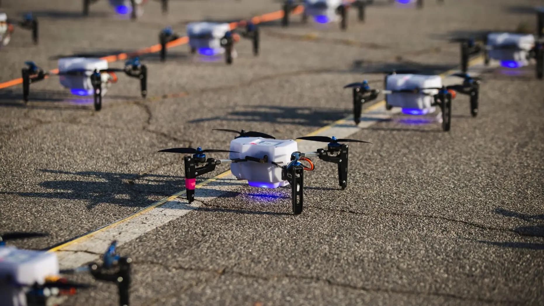 Rows of light show drones glow on the tarmac before takeoff.