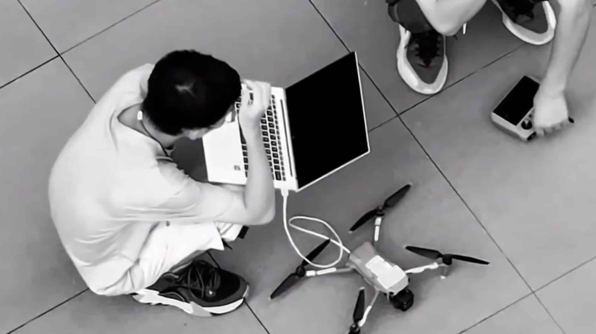 Tester sitting cross-legged with an open laptop tethered to the folding drone.