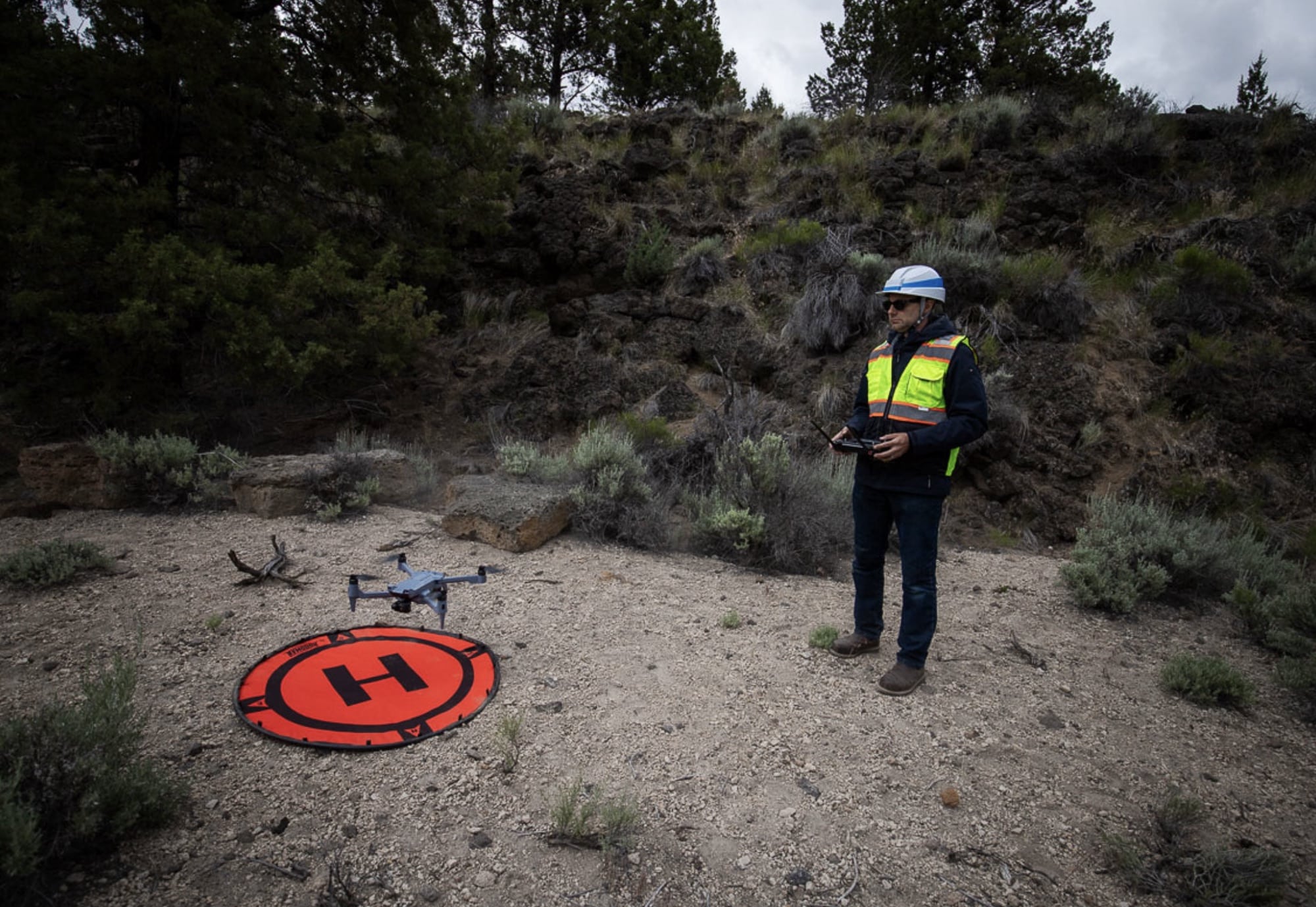 Pilot in a white hard hat standing beside the SOTEN and a landing pad.