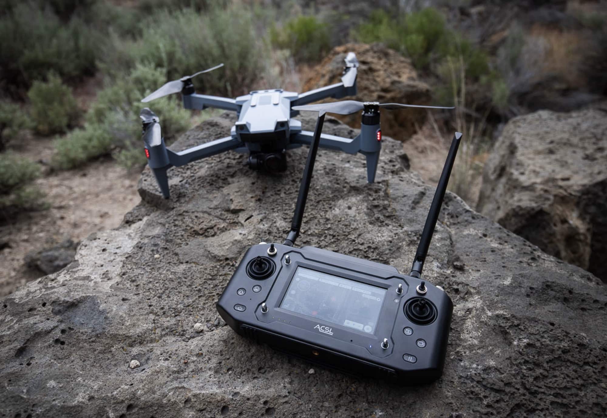 ACSL SOTEN drone and the TENSO controller resting together on rocky ground.
