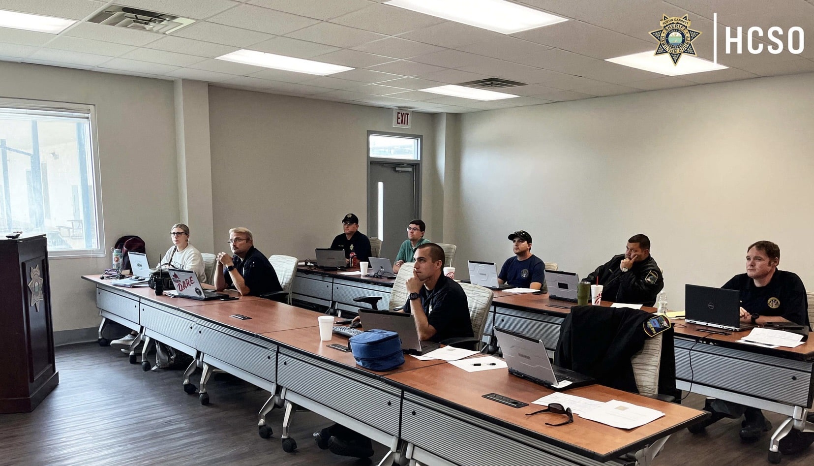 Deputies studying laptops at conference tables during Part 107 training in a classroom.