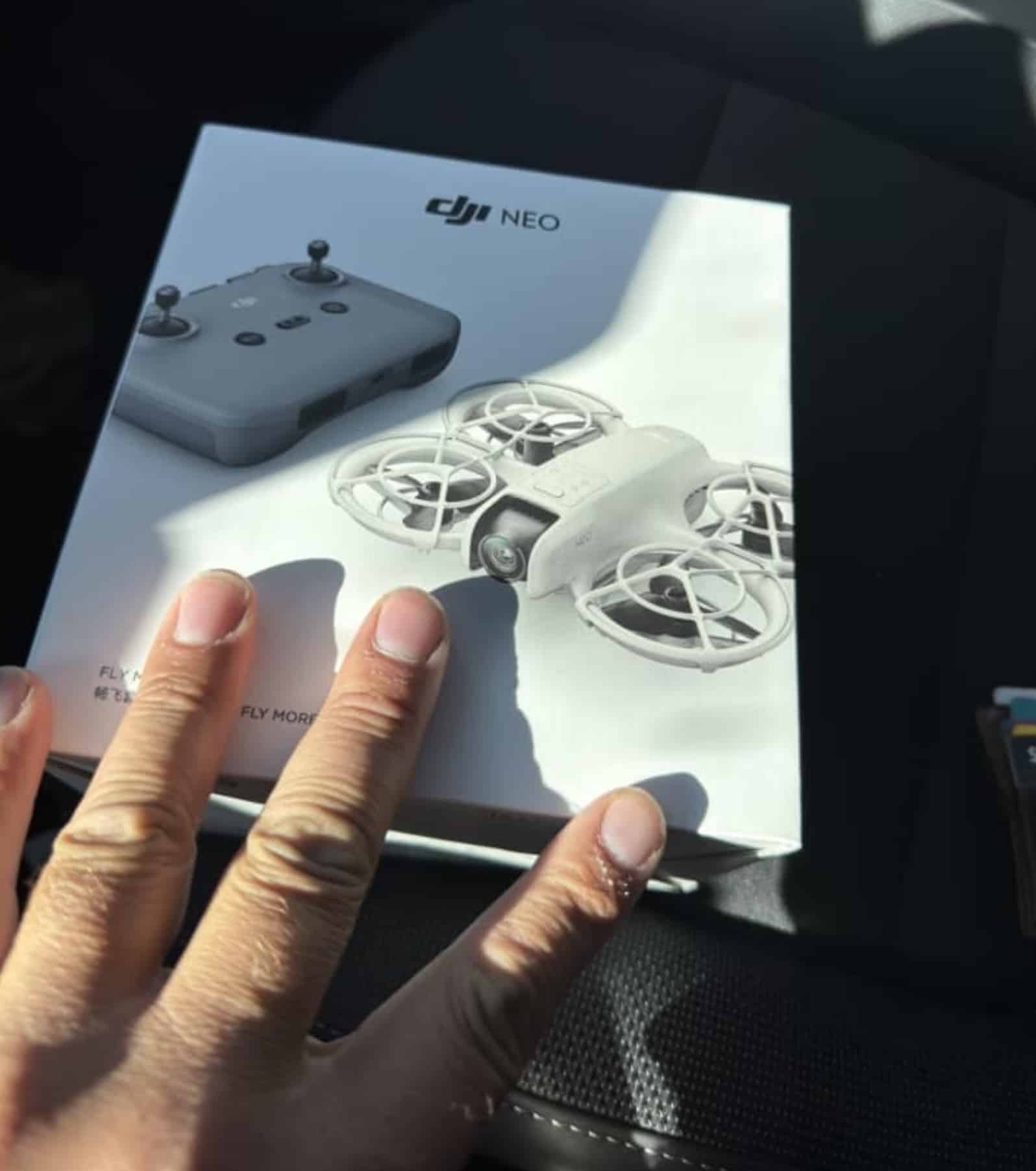 Hands holding a retail DJI Neo Fly More Combo box bought before launch.