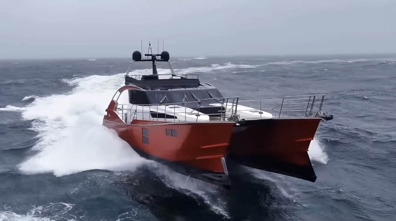 Orange power multihull Voyager driving through heavy swell, filmed from above.