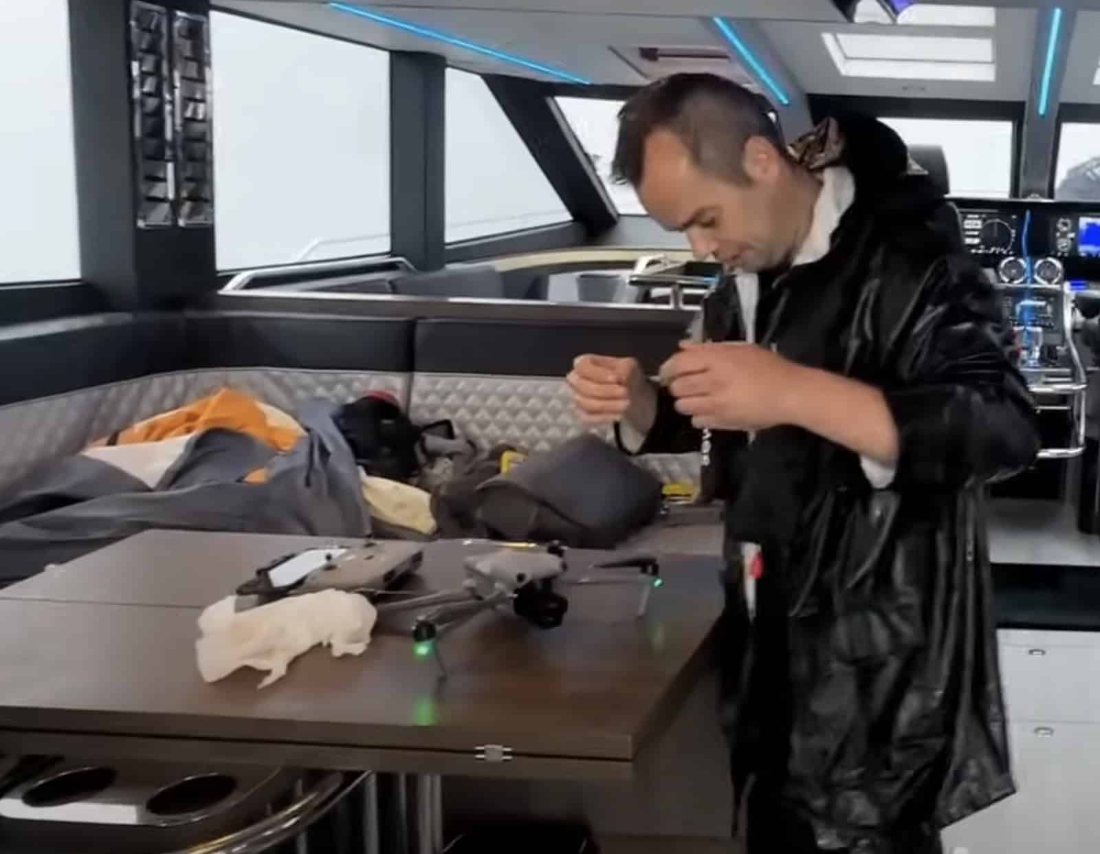 Crew member drying the recovered drone with a cloth at the saloon table.