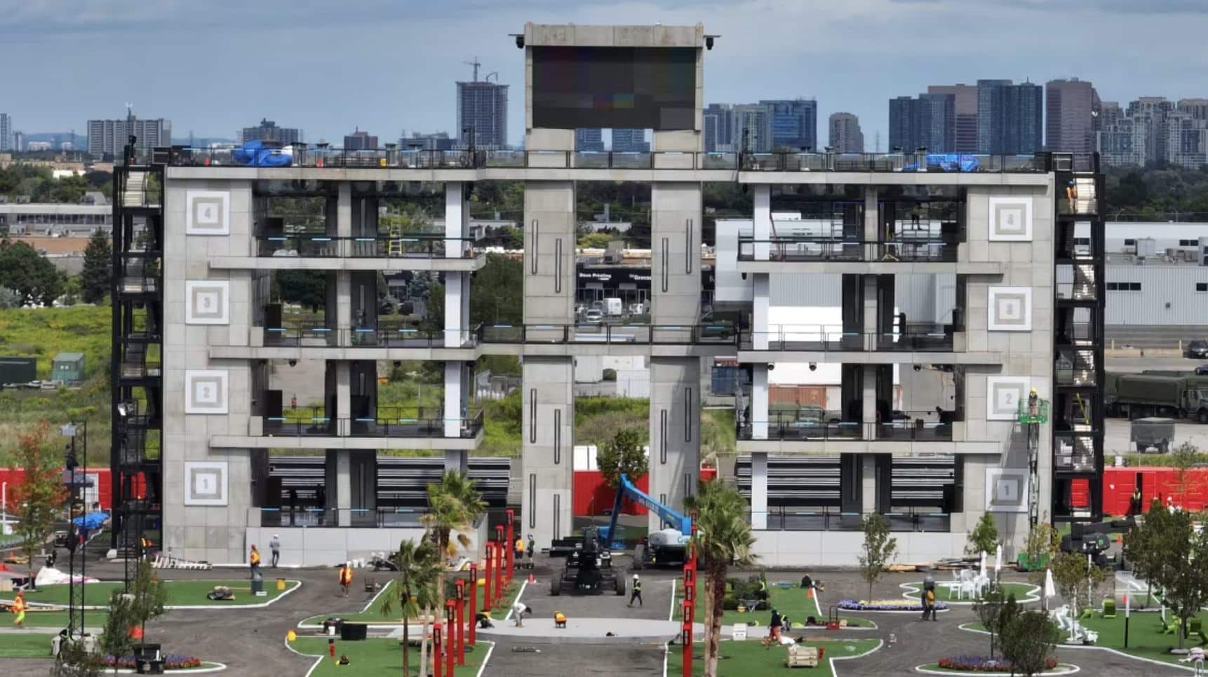 Multi-storey concrete tower at the edge of the set with crew and equipment below.