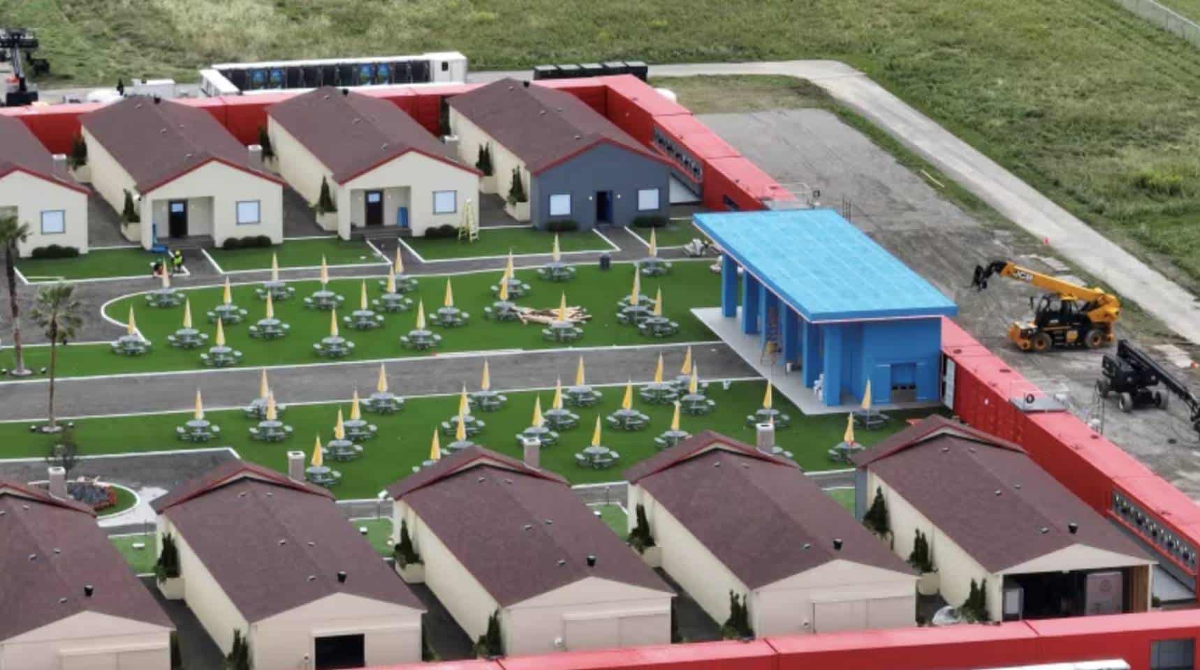 Aerial view of identical houses ringing lawns dotted with yellow umbrellas.