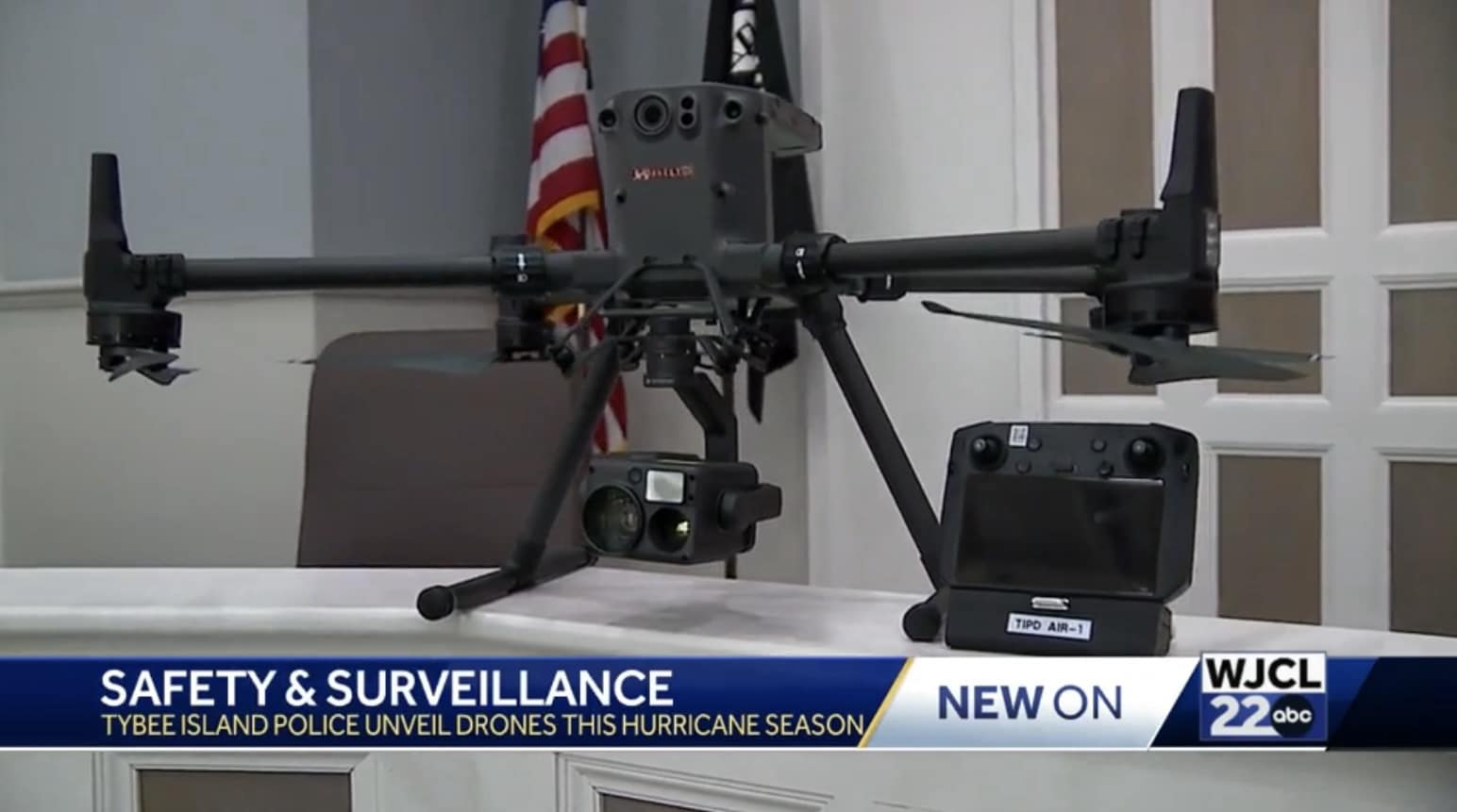 Police drone unfolded on a table beside its controller with a US flag behind.