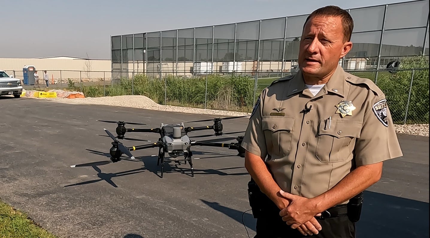 Weber County sheriff's deputy speaks beside the DJI FlyCart 30 parked on asphalt.