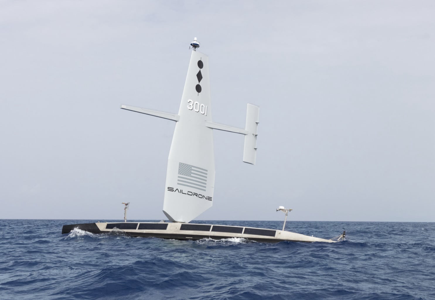 Saildrone Surveyor 3001 under its rigid wing sail on open blue water.