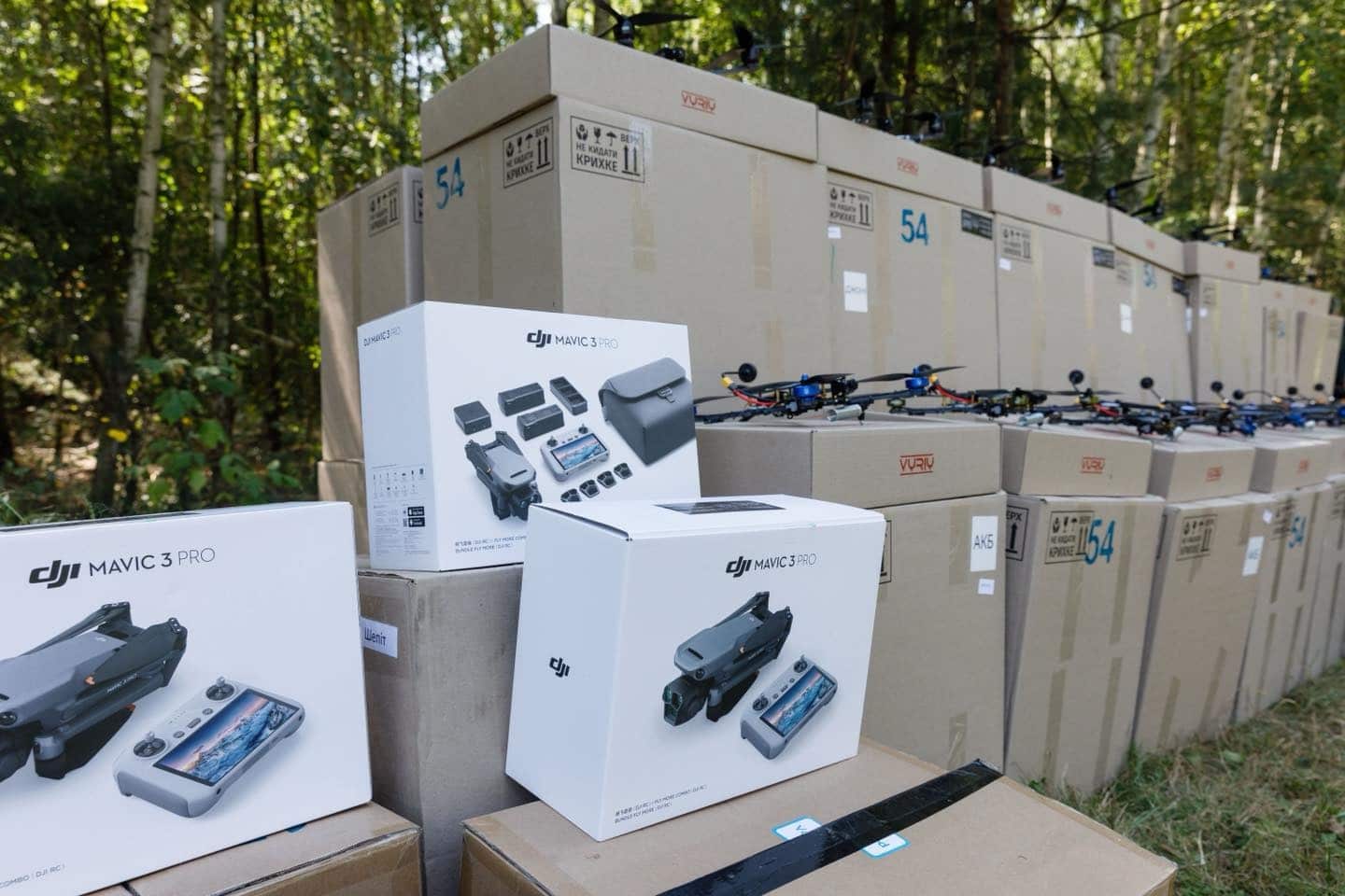 DJI Mavic 3 Pro retail boxes stacked in front of crated FPV drones.