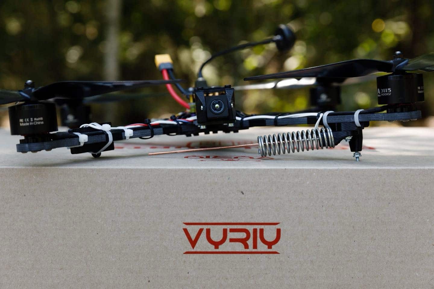 FPV drone frame with camera and antenna resting on a Vyriy-branded surface.