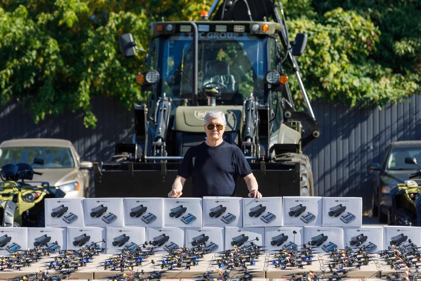 Gray-haired man standing behind rows of boxed DJI drones and FPV quadcopters.