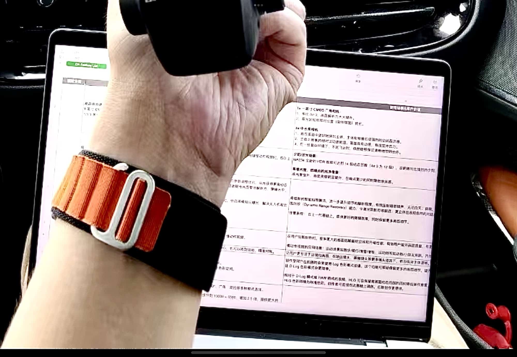 A wrist in front of a laptop displaying Chinese specification text for the drone.
