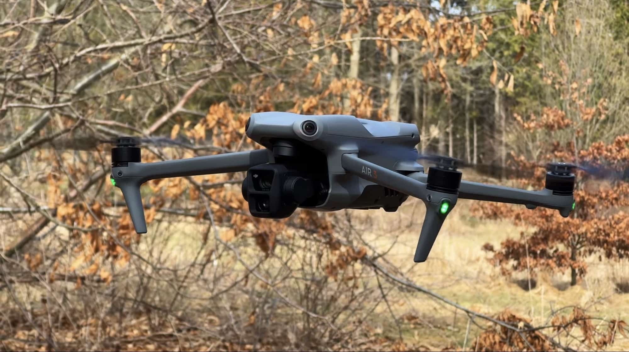 DJI Air 3 hovering among bare trees during a winter flight.