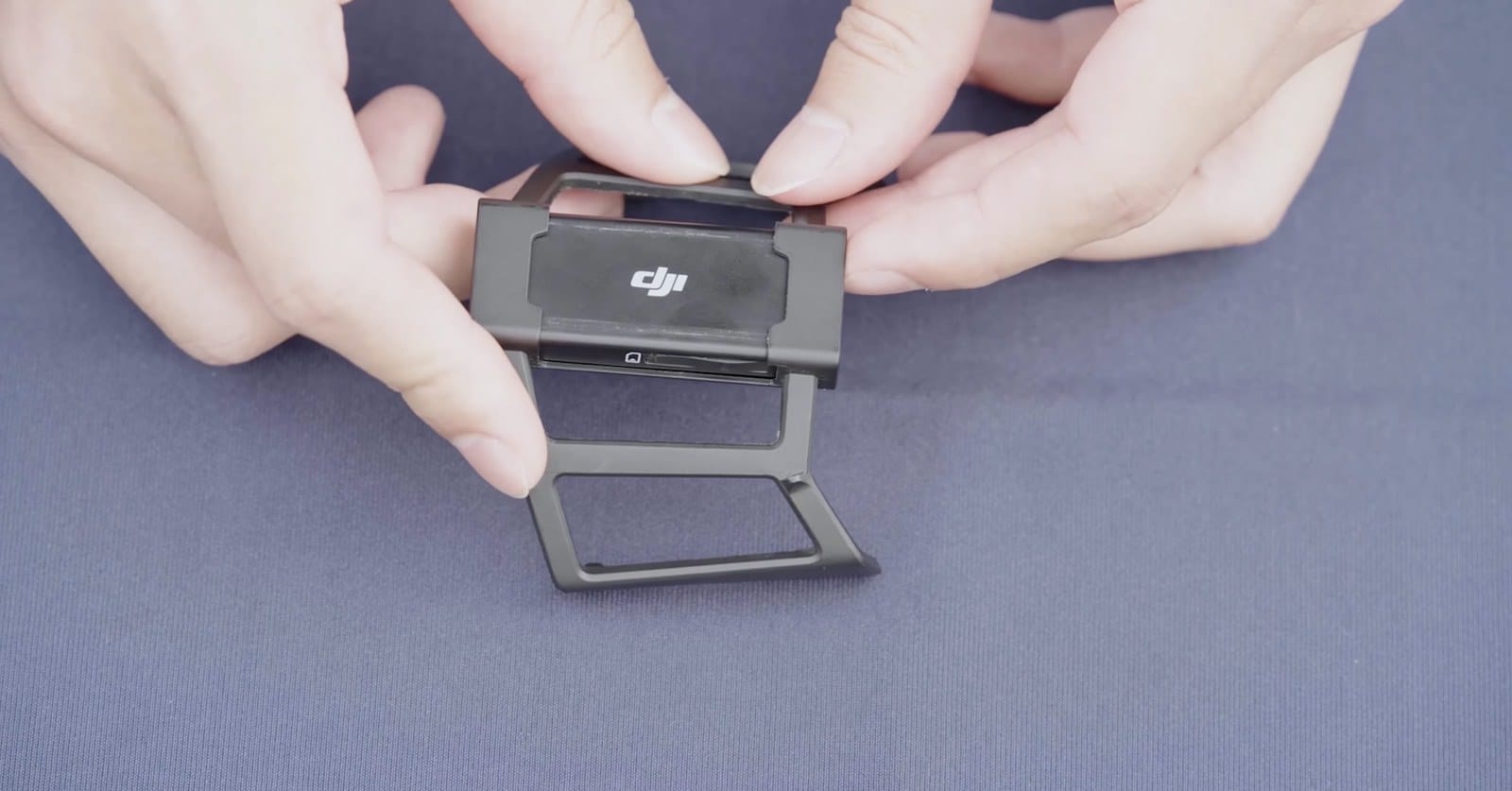 Hands unfolding the metal mounting bracket clipped to the back of the cellular dongle.