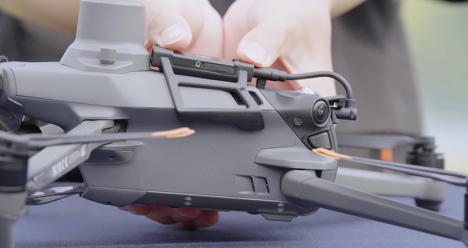 Hands routing the dongle cable forward along the drone body toward the gimbal.