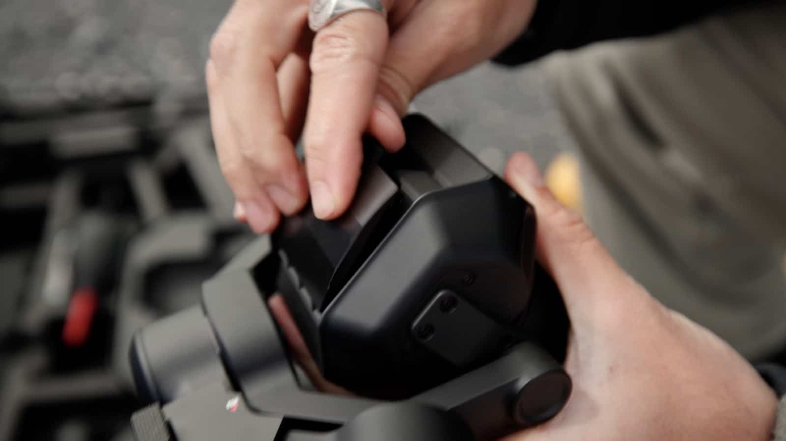 Hands mounting the 75mm f/1.8 lens onto the Inspire 3 X9 Air camera.