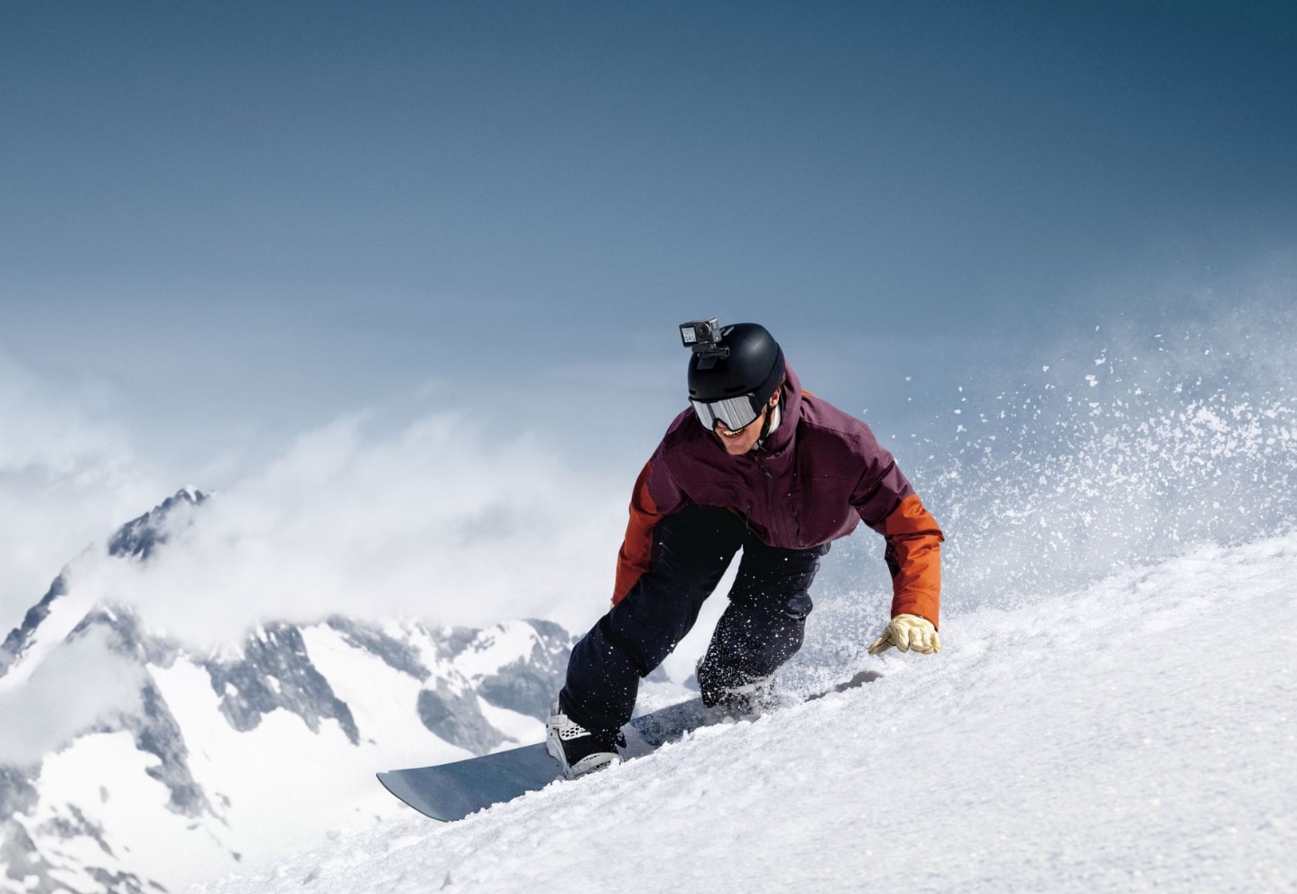 Snowboarder throwing up powder with the action camera mounted on his helmet.