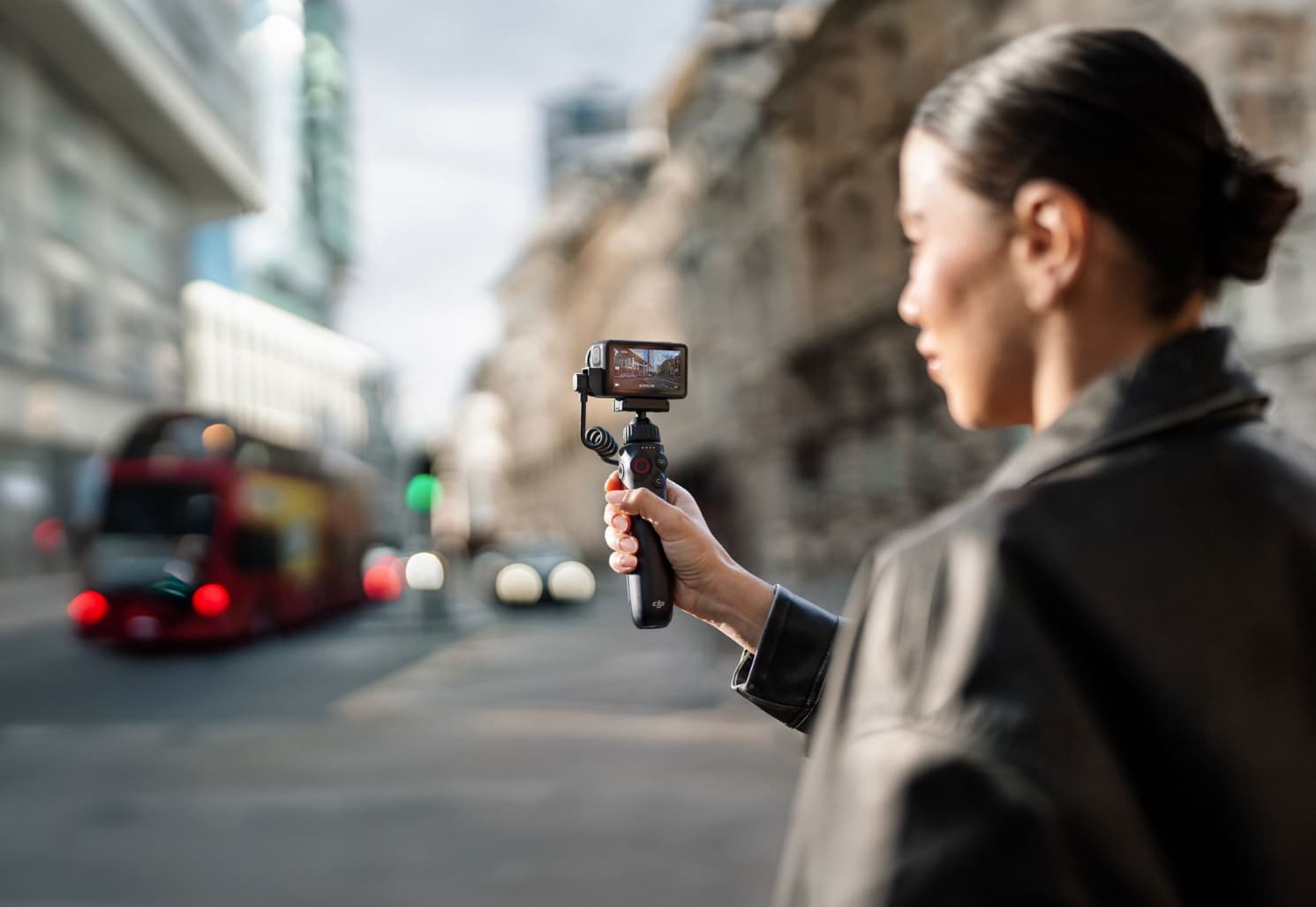 Woman filming herself on a London street as a red double-decker bus passes.
