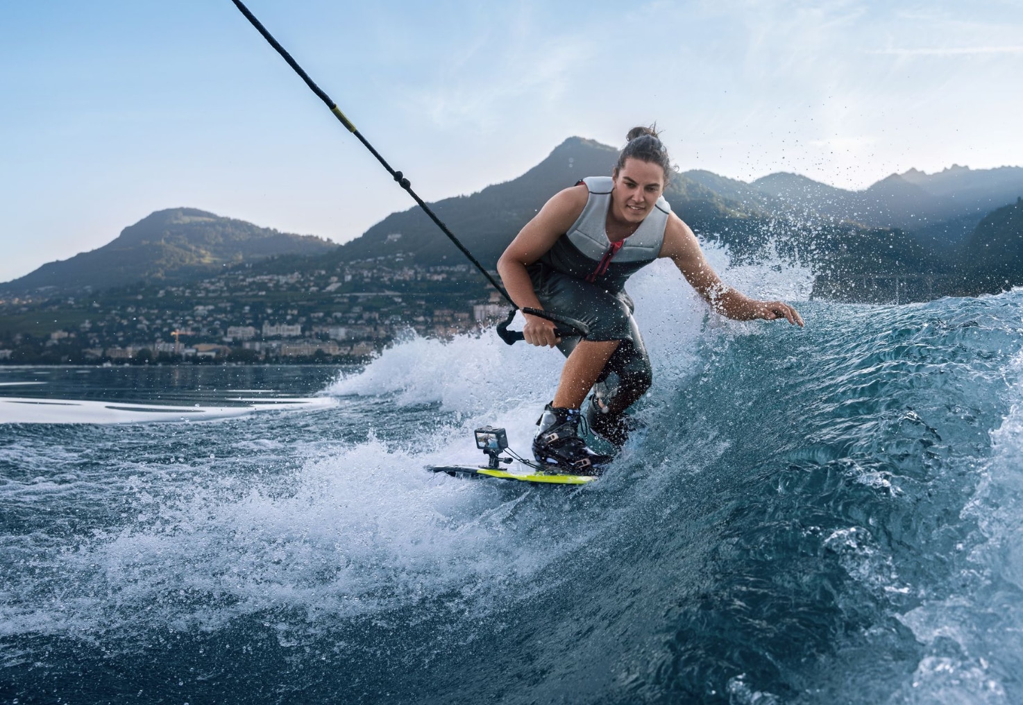 Wakesurfer carving a boat wake on an alpine lake with the camera board-mounted.