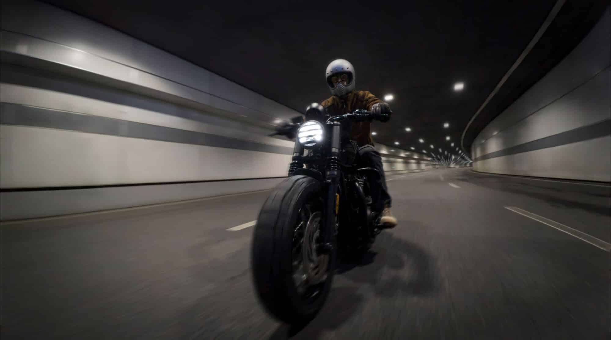 Motorcyclist riding through a tunnel with the walls streaking past in motion blur.