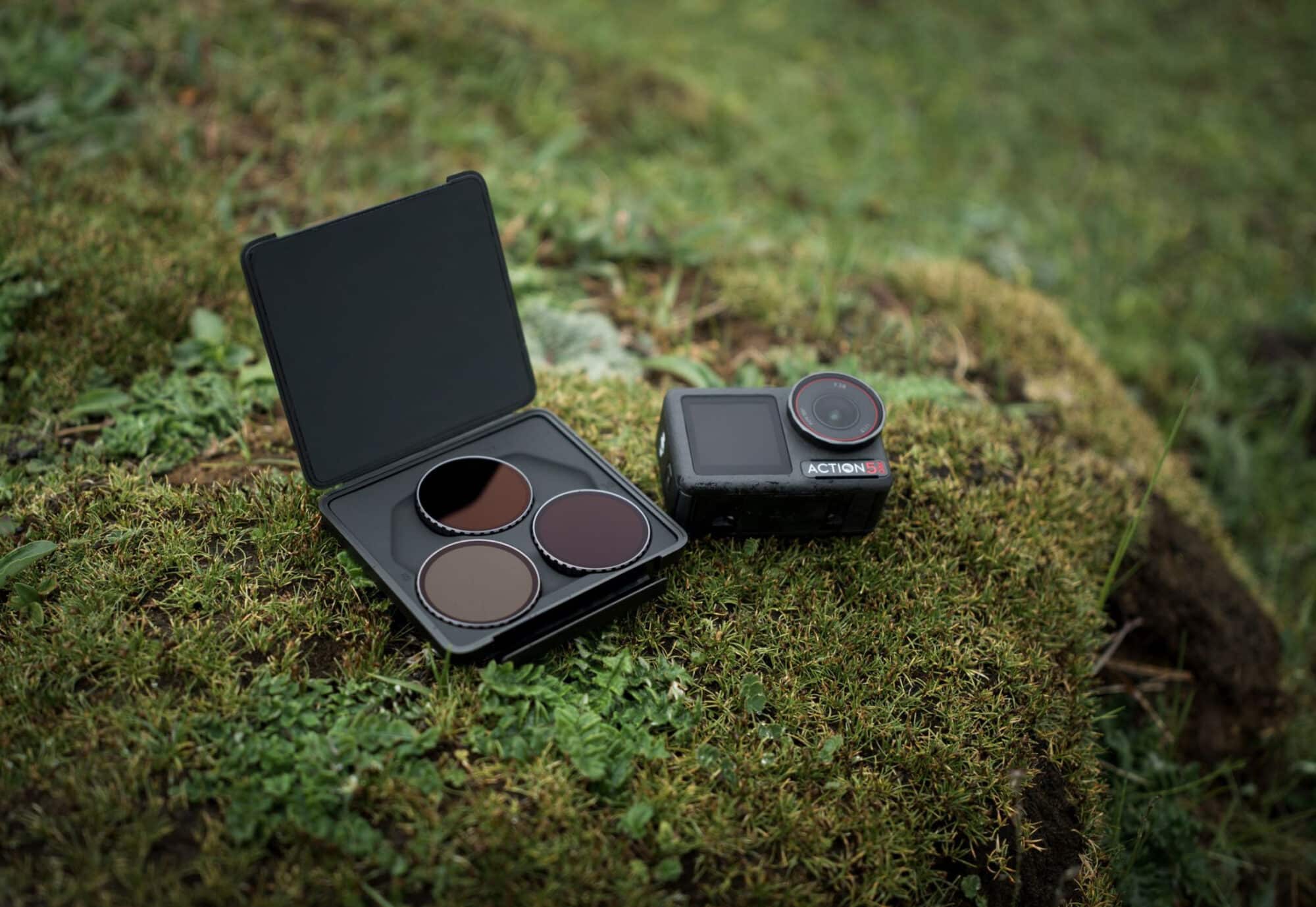 ND filter set open in its case on a mossy rock beside the camera.