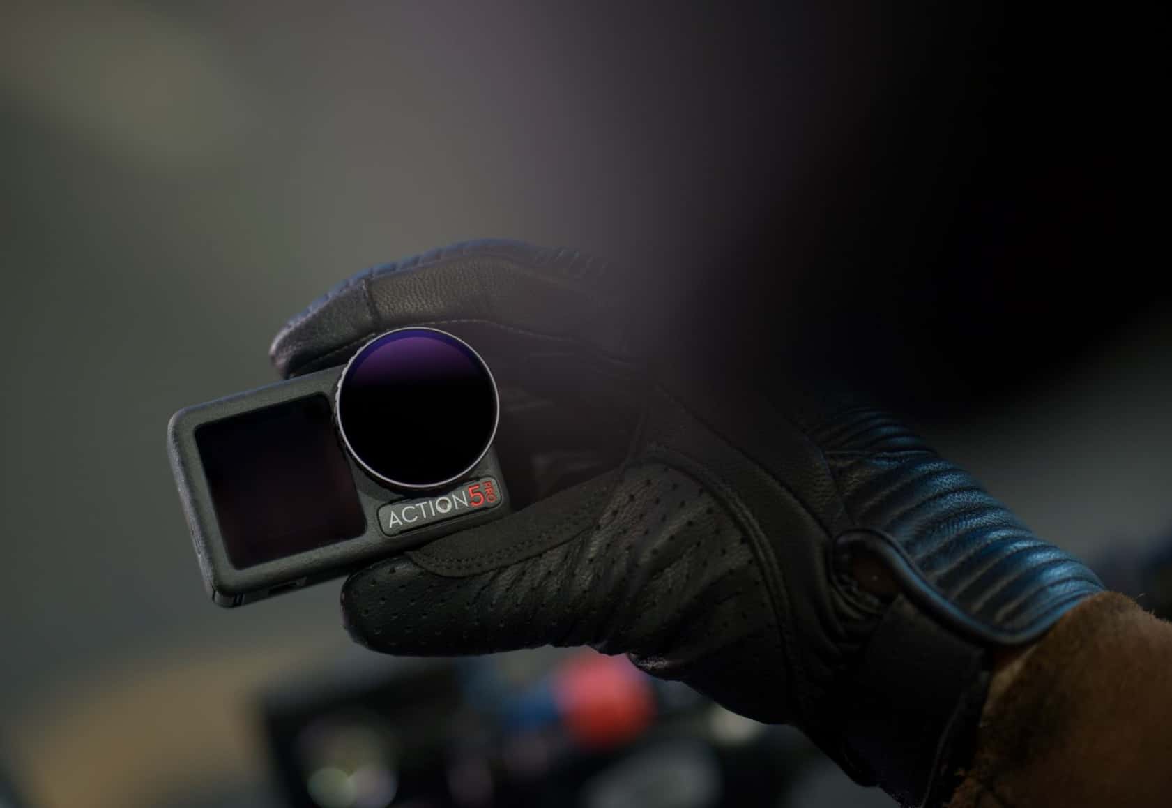 Gloved hand holding the Osmo Action 5 Pro with a magnetic ND filter fitted.