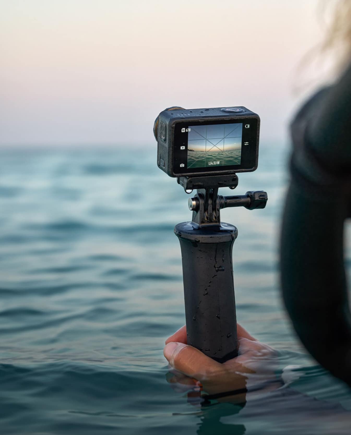 Camera on a floating hand grip half submerged in calm sea at dusk.
