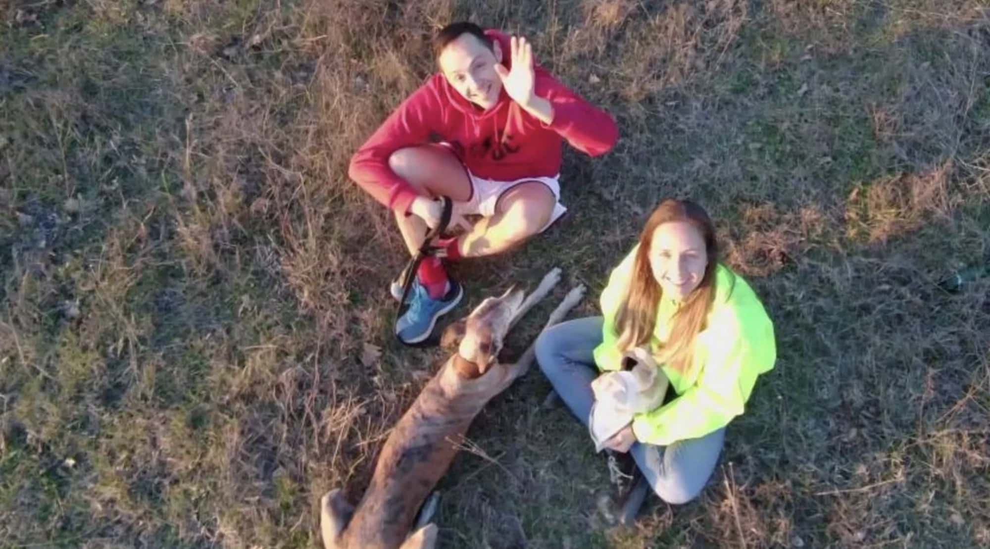 Recovered drone footage showing a couple and their dog waving upward from grass.