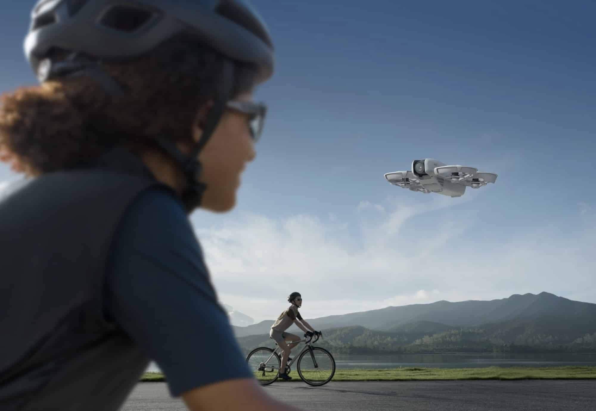 A helmeted cyclist looks on as the Neo flies beside a lakeside road.