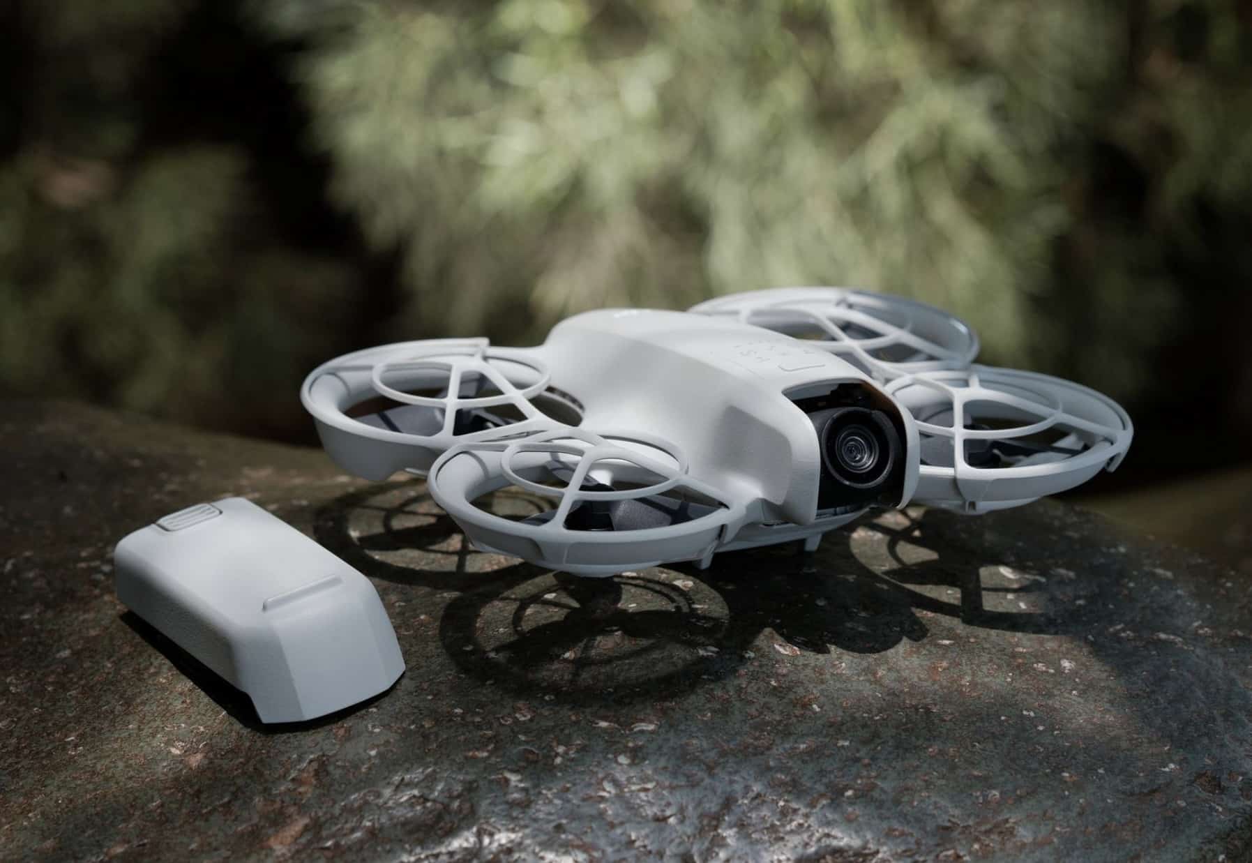 The Neo sits on a mossy rock next to a spare flight battery.