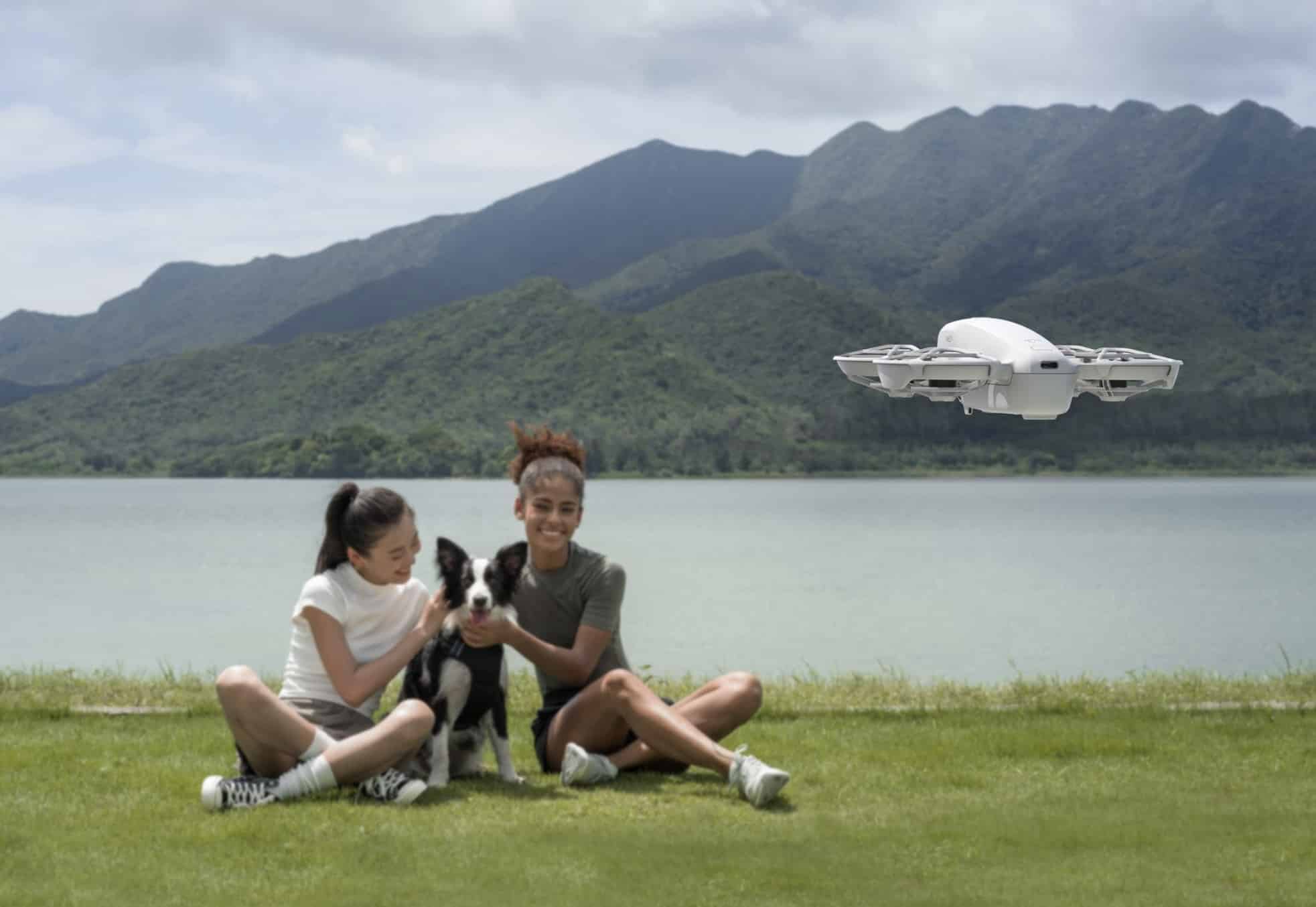The Neo hovers high over a lakeside lawn where a pair sit with their dog.