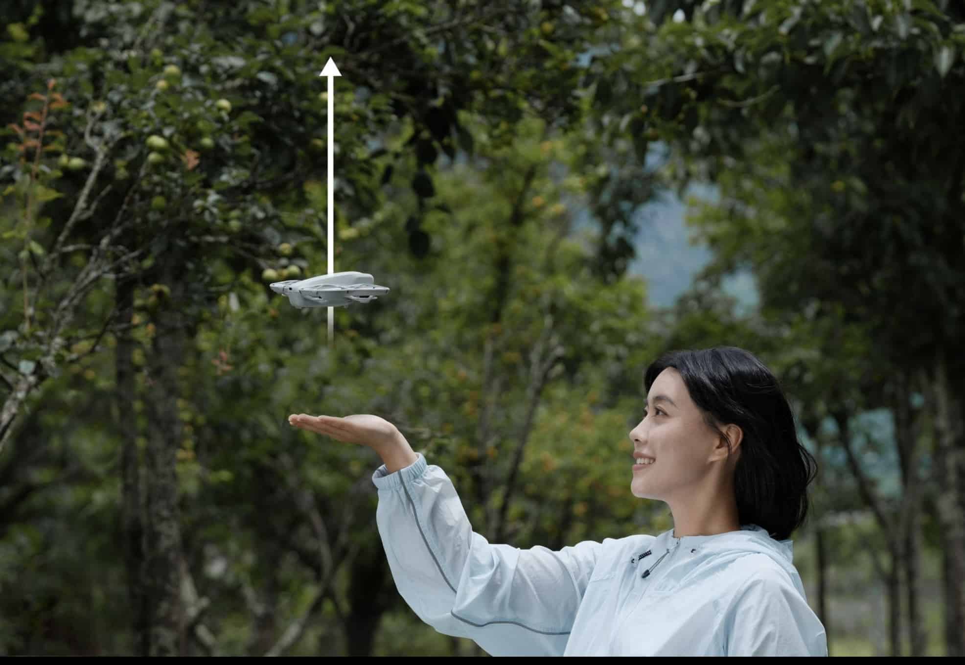 White arrow traces the DJI Neo climbing straight up from a woman's outstretched hand.
