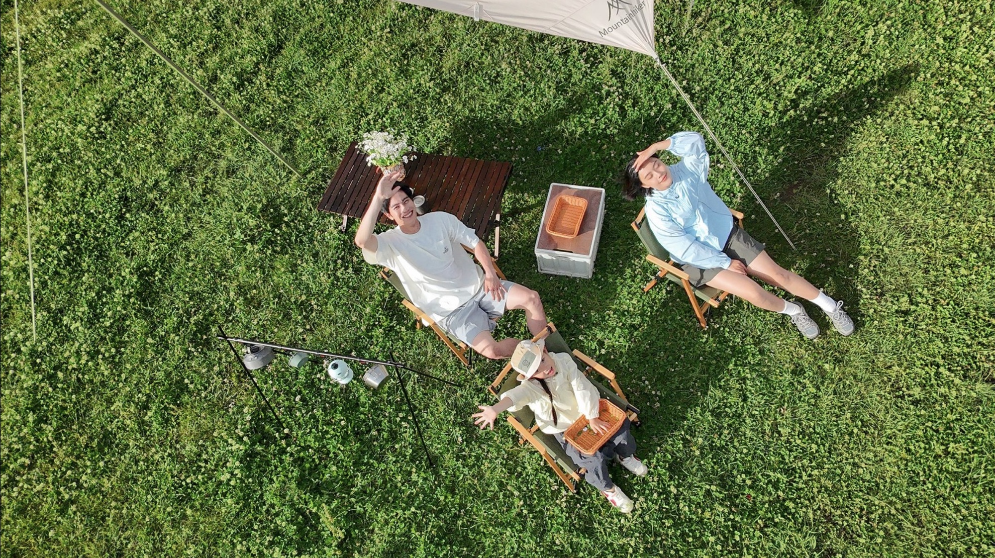 Overhead Neo shot of two people relaxing on grass beneath a picnic canopy.
