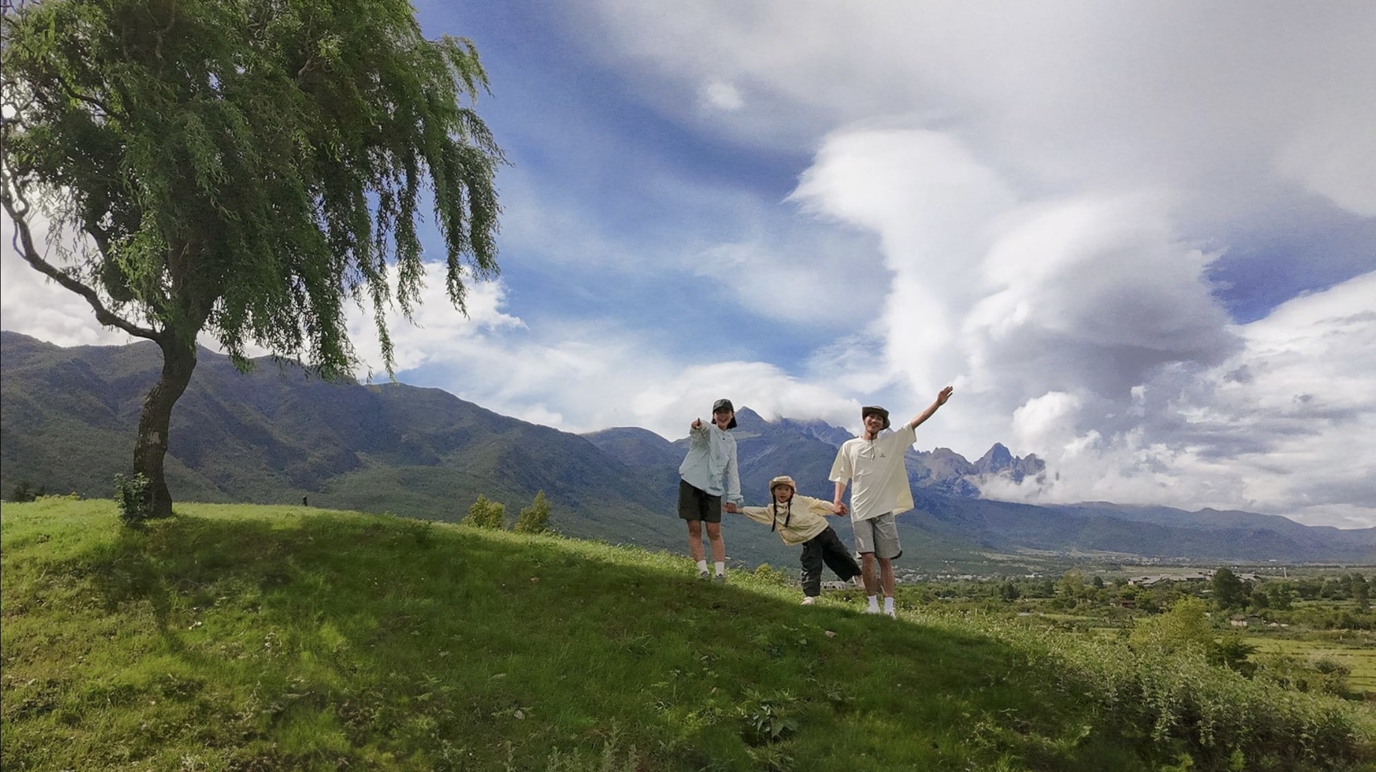 Neo landscape frame of three people on a grassy hill under a willow tree.